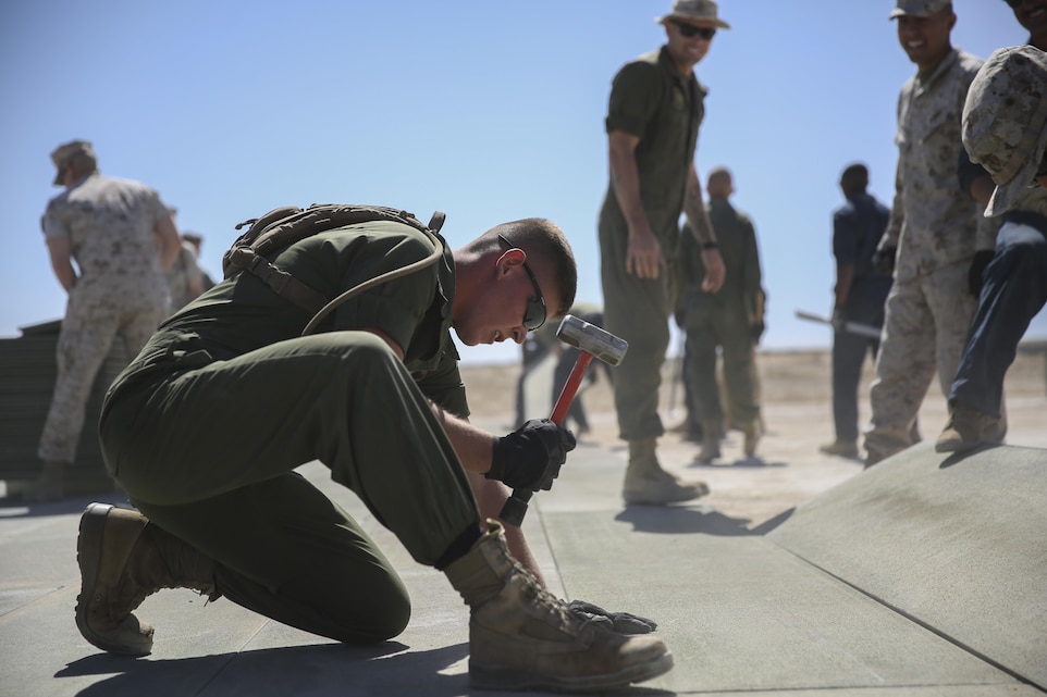 Lance Cpl. Tanner J. Clayson, Expeditionary Airfield Systems Technician, Marine Wing Support Squadron 372, pounds an aluminum panel into place during a refurbishing project on the Strategic Expeditionary Landing Field at Camp Wilson, March 23, 2015. Clayson is one of eight Marines who came from Marine Corps Base Camp Pendleton to help with the work on the SELF. (Official Marine Corps photo by Pfc. Levi Schultz/Released)