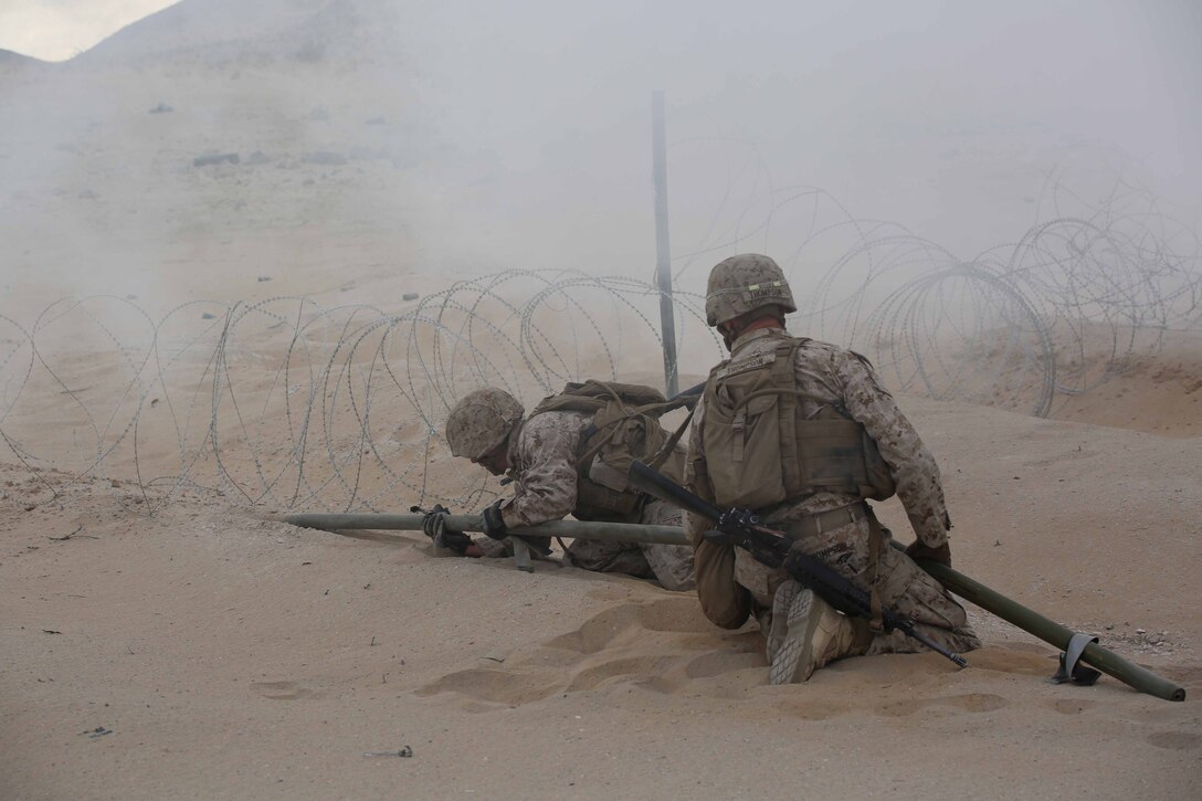 Marines with Engineer Platoon, Headquarters and Service Company, Ground Combat Element Integrated Task Force, snap M1A2 Bangalores together under the concealment of smoke for a hasty breach during a Marine Corps Operational Test and Evaluation Activity assessment at Range 107, Marine Corps Air Ground Combat Center Twentynine Palms, California, March 22, 2015. From October 2014 to July 2015, the GCEITF will conduct individual and collective level skills training in designated ground combat arms occupational specialties in order to facilitate the standards-based assessment of the physical performance of Marines in a simulated operating environment performing specific ground combat arms tasks. (U.S. Marine Corps photo by Cpl. Paul S. Martinez/Released)