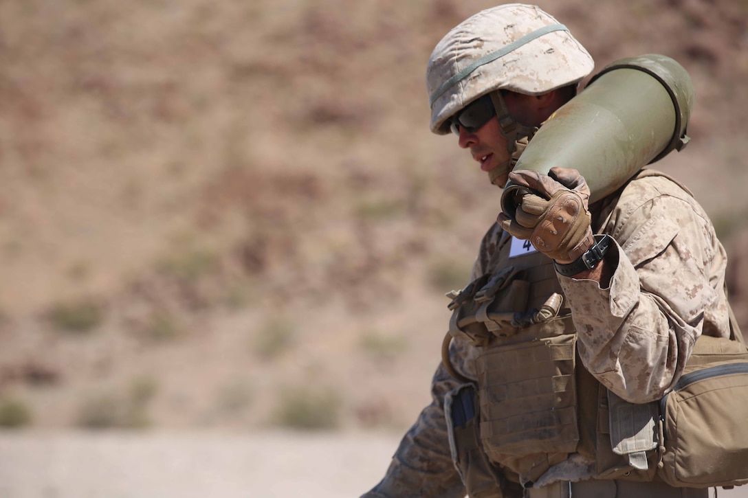 Cpl. Joshua J. Syverson, combat engineer, Engineer Platoon, Headquarters and Service Company, Ground Combat Element Integrated Task Force, carries a 155mm shell during cache reduction as part of a Marine Corps Operational Test and Evaluation Activity assessment at Range 114, Marine Corps Air Ground Combat Center Twentynine Palms, California, March 23, 2015.  From October 2014 to July 2015, the GCEITF will conduct individual and collective level skills training in designated ground combat arms occupational specialties in order to facilitate the standards-based assessment of the physical performance of Marines in a simulated operating environment performing specific ground combat arms tasks. (U.S. Marine Corps photo by Cpl. Paul S. Martinez/Released)