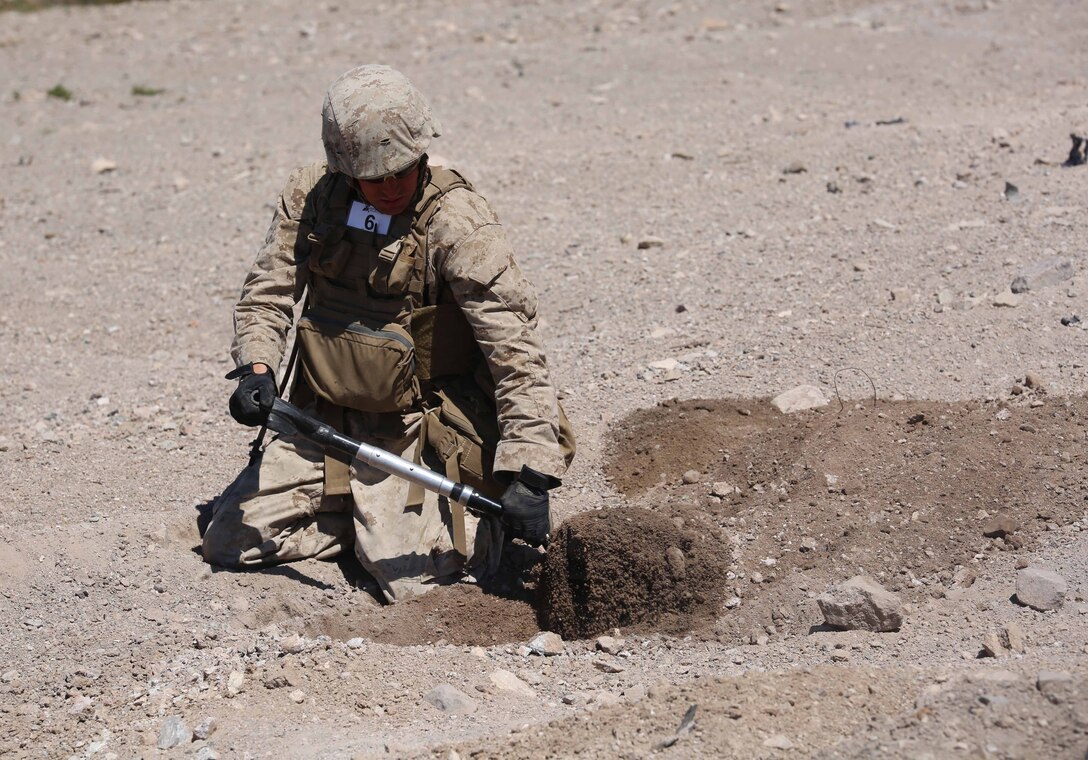 Cpl. Travis Smith, combat engineer, Engineer Platoon, Headquarters and Service Company, Ground Combat Element Integrated Task Force, digs a hole during cache reduction as part of a Marine Corps Operational Test and Evaluation Activity assessment at Range 114, Marine Corps Air Ground Combat Center Twentynine Palms, California, March 23, 2015.  From October 2014 to July 2015, the GCEITF will conduct individual and collective level skills training in designated ground combat arms occupational specialties in order to facilitate the standards-based assessment of the physical performance of Marines in a simulated operating environment performing specific ground combat arms tasks. (U.S. Marine Corps photo by Cpl. Paul S. Martinez/Released)