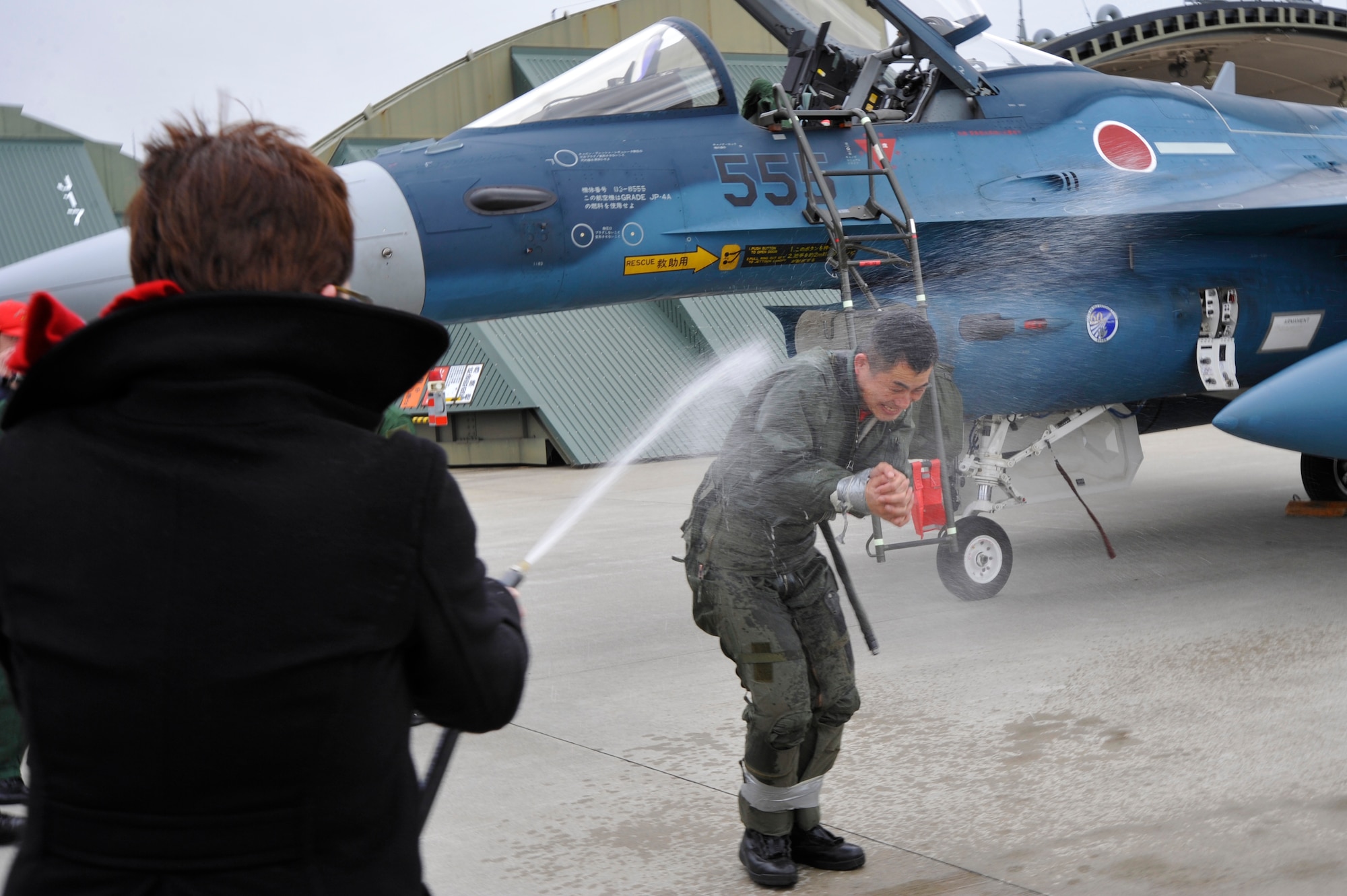 Japan Air Self-Defense Force Lt. Col. Katsushi "Kitty" Hashimoto, 3rd Tactical Fighter Squadron commander, is hosed down with water by his wife as part of a fini-flight celebration at Misawa Air Base, Japan, March 23, 2015. Unlike a more formal Japanese setting for a fini-flight, Hashimoto received an American-style hose down with water and champagne by coworkers, family and friends from the 35th Fighter Wing. (U.S. Air Force photo by Senior Airman Jose L. Hernandez-Domitilo/Released)
