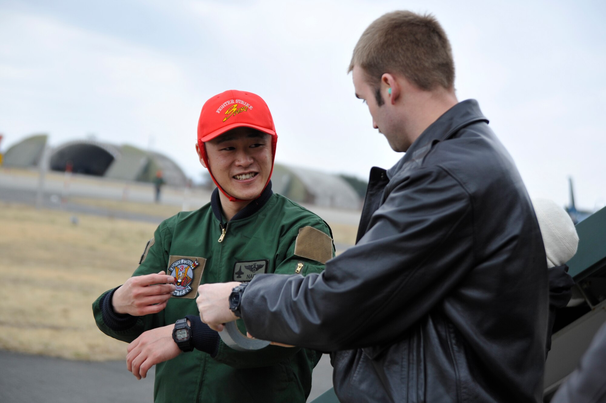 U.S. Air Force 1st Lt. Matthew Lavigne, 13th Fighter Squadron pilot, speaks to a member of the Japan Air Self-Defense Force about the traditions and customs of how American F-16 Fighting Falcon pilots perform fini-flights at Misawa Air Base, Japan, March 23, 2015. The tradition for a Japanese pilot's final flight at a duty location is often more formal than the livelier atmosphere of American-style fini-flights. (U.S. Air Force photo by Senior Airman Jose L. Hernandez-Domitilo/Released)