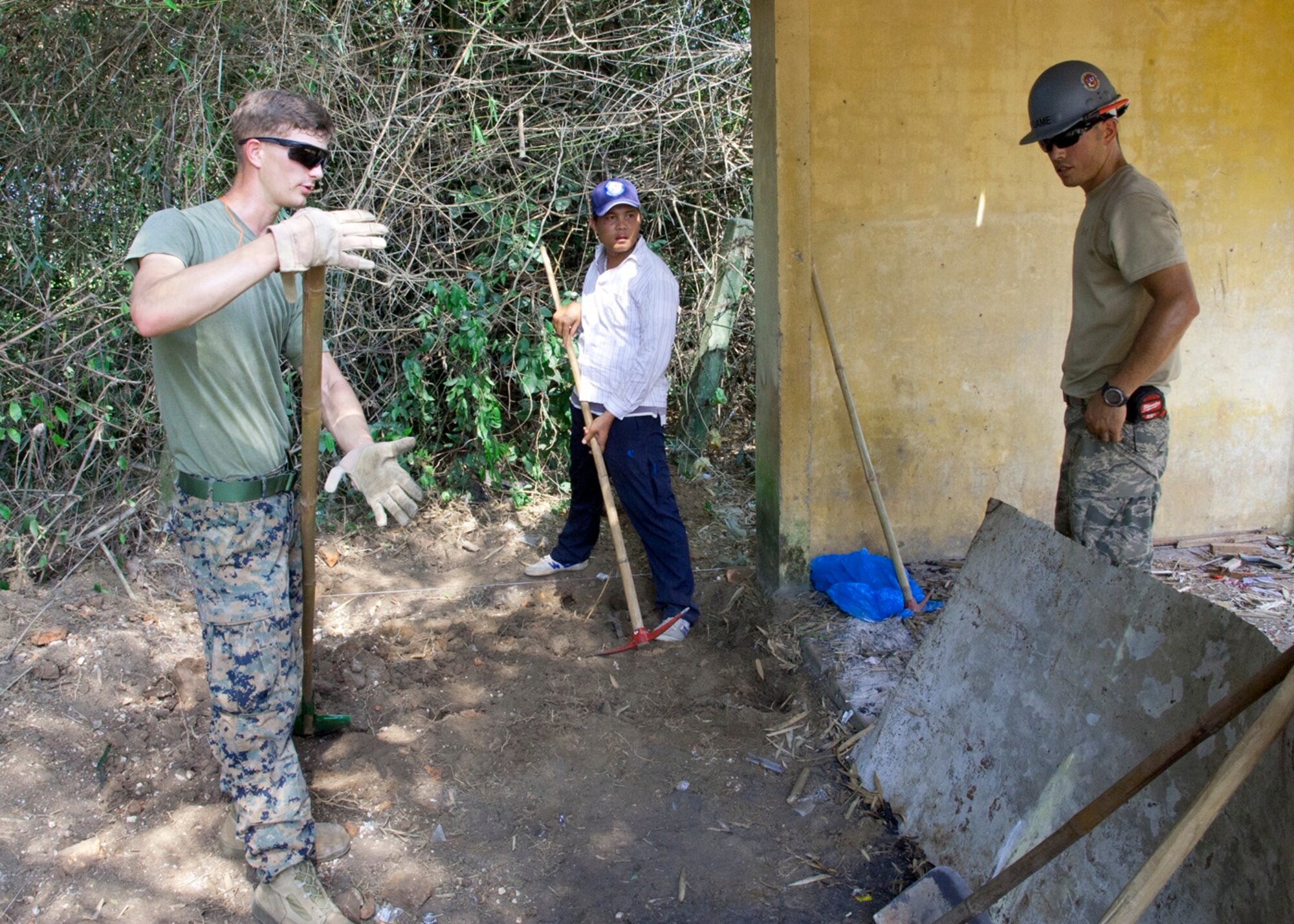 U.S. servicemembers and a Vietnam People's Army Defense member, middle, discuss the progress of preparing a site for pouring a concrete pad at Binh Thanh Dong primary school, Quang Ngai Province, Vietnam, during a Operation Pacific Angel 15-3 event, March 23, 2015. This is the fifth time PACANGEL has partnered with the host nation to provide humanitarian assistance and disaster relief in the region.  (U.S. Air Force photo by Staff Sgt. Tong Duong/ Released)