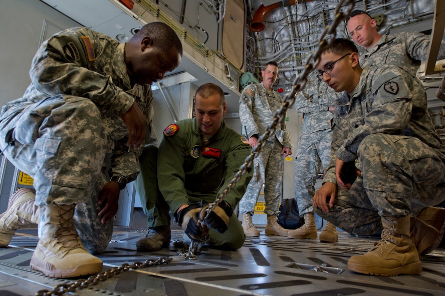Senior Airman Glenn Martin, a loadmaster from the 535th Airlift Squadron, shows soldiers from the 2nd Brigade, 25th Infantry Division, how to use restraints to secure a tactical base of operation vehicle that is loaded in a C-17 Globemaster III on Joint Base Pearl Harbor-Hickam, Hawaii, March 18, 2015. The training is essential for the 25th ID soldiers that are a part of a contingence response force that responds to any type of operation within the Pacific’s area of responsibility. (U.S. Air Force photo by Tech. Sgt. Aaron Oelrich/Released)               