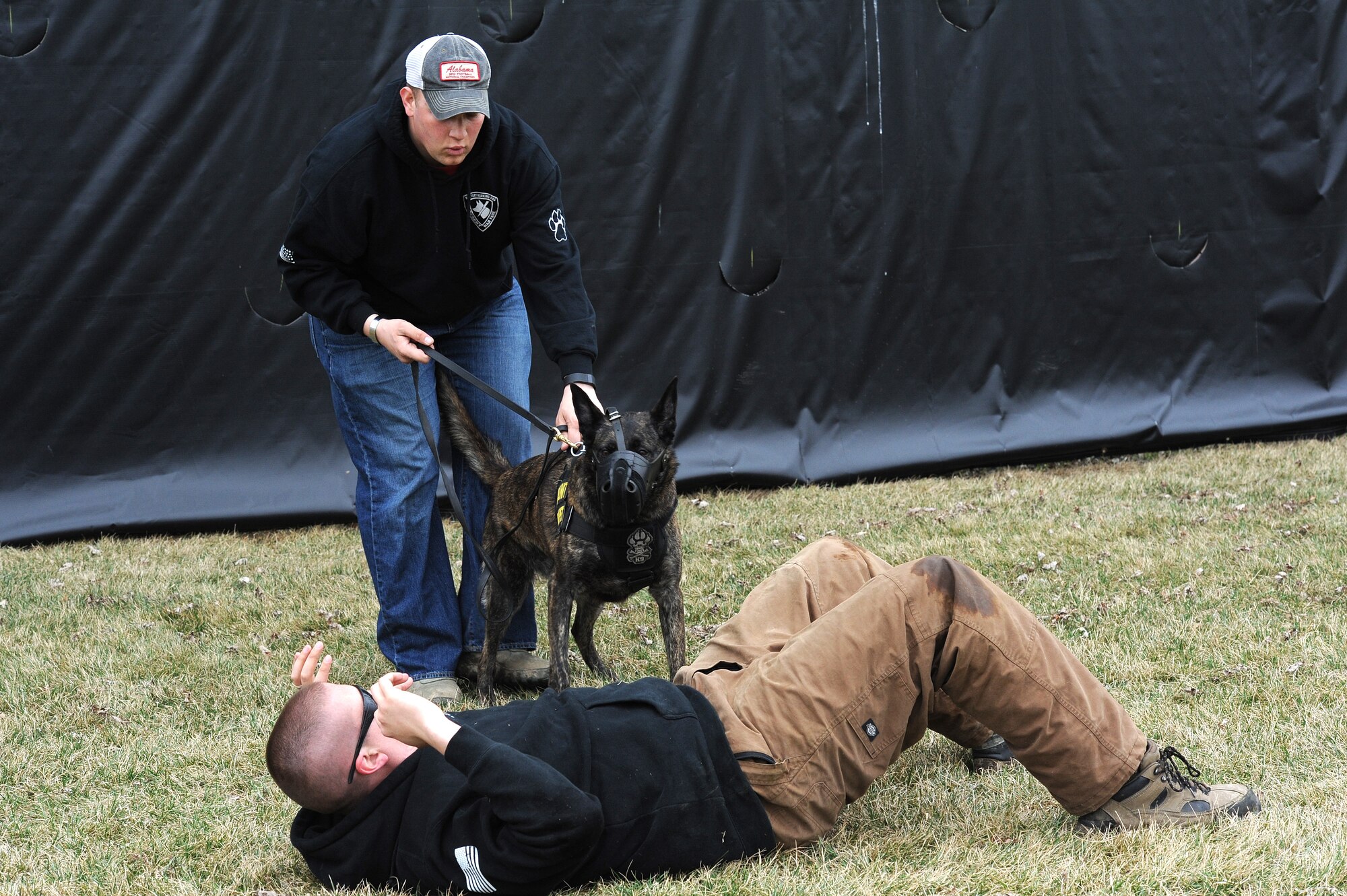 Staff Sgt. David Yaronczyk, 375th Security Forces Squadron military working dog handler, calls out commands to Tech. Sgt. Bryan Dell, 375th SFS NCOIC military working dog section, as Fay, 375th SFS military working dog, watches during muzzle aggression training March 20, 2015, at the 375th SFS Military Working Dog Kennels at Scott Air Force Base, Ill. At approximately nine months old the K-9’s start training and must go through a 120 day basic training course where they learn basic obedience and either become a drug or bomb dog. (U.S. Air Force photo/ Senior Airman Tristin English)