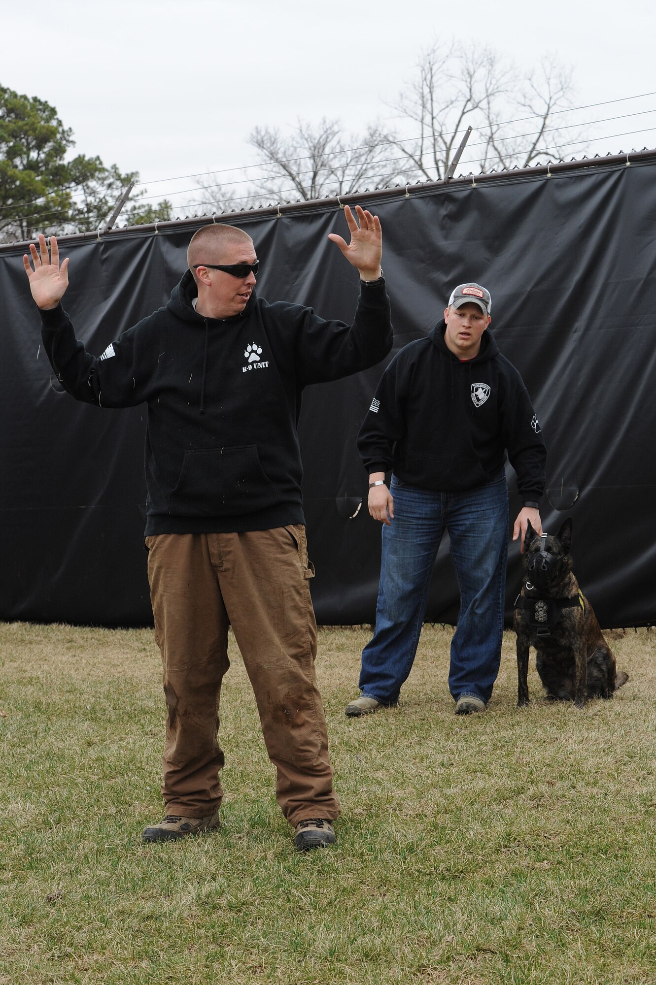 Staff Sgt. David Yaronczyk, 375th Security Forces Squadron military working dog handler, calls out commands to Tech. Sgt. Bryan Dell, 375th SFS NCOIC military working dog section, as Fay, 375th SFS military working dog, watches during muzzle aggression training March 20, 2015, at the 375th SFS Military Working Dog Kennels at Scott Air Force Base, Ill. At approximately nine months old the K-9’s start training and must go through a 120 day basic training course where they learn basic obedience and either become a drug or bomb dog. (U.S. Air Force photo/ Senior Airman Tristin English)
