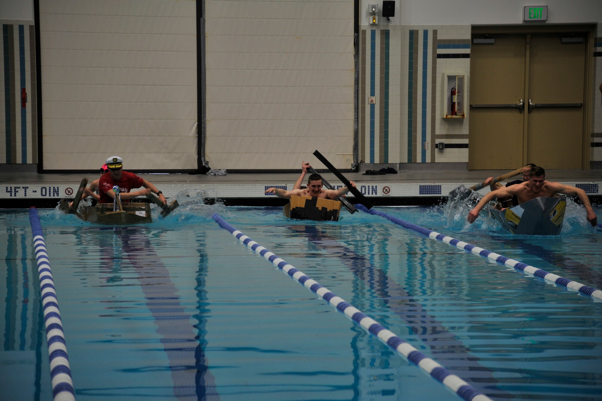 The 92nd Air Refueling Wing Wing Staff Agencies, 92nd Communications Squadron and 92nd Contracting Squadron race to the end of the base pool during Winter Sports Day, March 20, 2015, at Fairchild Air Force Base, Wash. To participate in the race, each team had to build a boat out of cardboard and two rolls of duct tape. The teams raced across the pool with the fastest time winning the race. (U.S. Air Force photo/Airman 1st Class Taylor Bourgeous)