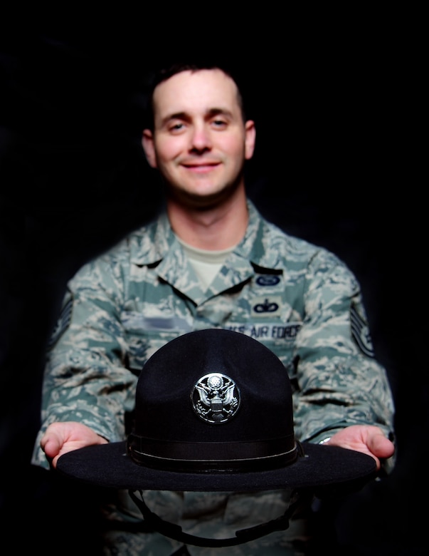 U.S. Air Force Tech. Sgt. Dewhite, 36th Intelligence Squadron geospatial systems noncommissioned officer in charge, displays his Air Force Basic Military Training Instructor campaign hat at Langley Air Force Base, Va., March 9, 2015. Dewhite said he continues to embody his former Air Force Military Training Instructor spirit by maintaining a high level of standards and continuing to instill the importance of the Air Force core values in the Airmen around him. (U.S. Air Force photo illustration by Senior Airman Aubrey White)(The last name of the subject has been withheld for operational security purposes.)