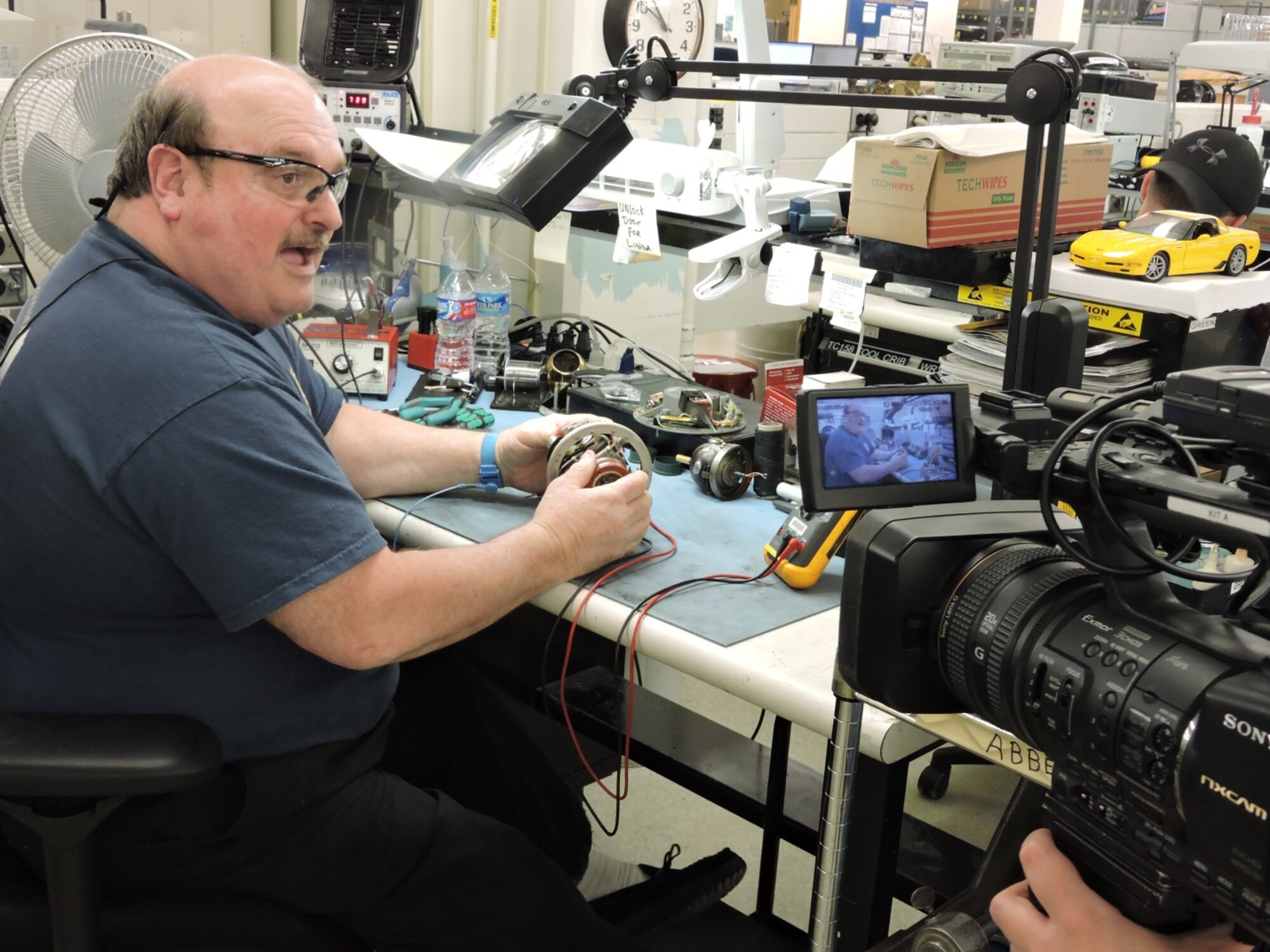 Abbey Green, 566th Electronics Maintenance Squadron electronics mechanic, tells how he installs the many components used in a gyroscope assembly. The 566th EMXS Gyro Shop will be featured on 13WMAZ's "Behind the Lines" segment airing on the March 26th Eyewitness News telecast at 6 p.m. (U.S. Air Force photo by Roland Leach)