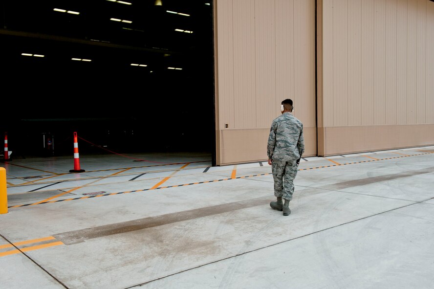Tech. Sgt. Aldwin Del Rosario, 49th Aircraft Maintenance Squadron Avionic expeditor, supervises the opening of a hangar door on the flightline at Holloman Air Force Base, N.M. March 18, 2015. Del Rosario and flight members prepared to perform a 28-Day Inspection, a time compliance inspection on the batteries. (U.S. Air Force photo by Staff Sgt. E’Lysia A. Wray/Released)