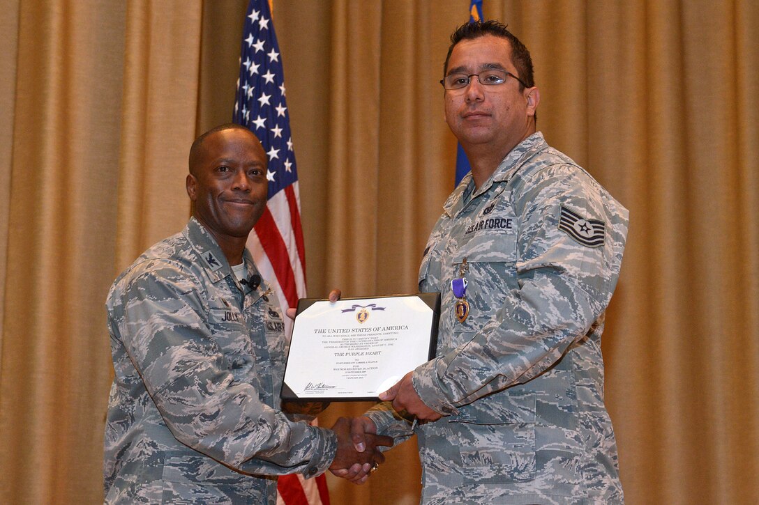 Col. Ron Jolly, 75th Air Base Wing and Installation commander, right, presented Tech. Sgt. Gabriel Wasnuk with the Purple Heart during a commander's call at Hill Air Force Base march 25. Wasnuk was awarded the purple heart for brain injuries he sustained during two deployments to Iraq and Afghanistan as an Explosive Ordnance Technician, where he was in the area of six improvised explosive blasts. (U.S. Air Force/Alex R. Lloyd)