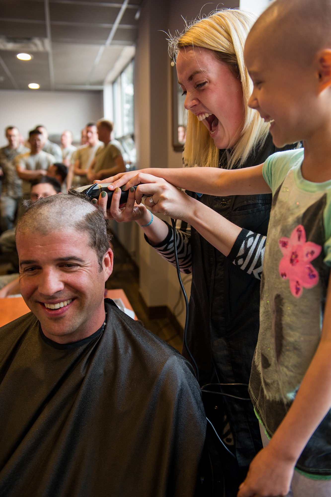 Maj. Nathan Litz, 419th Fighter Wing chief of safety, gets his head shaved with help from his daughter, Gracie, who is undergoing chemotherapy to battle lymphoblastic lymphoma. (U.S. Air Force photo/R. Nial Bradshaw)
