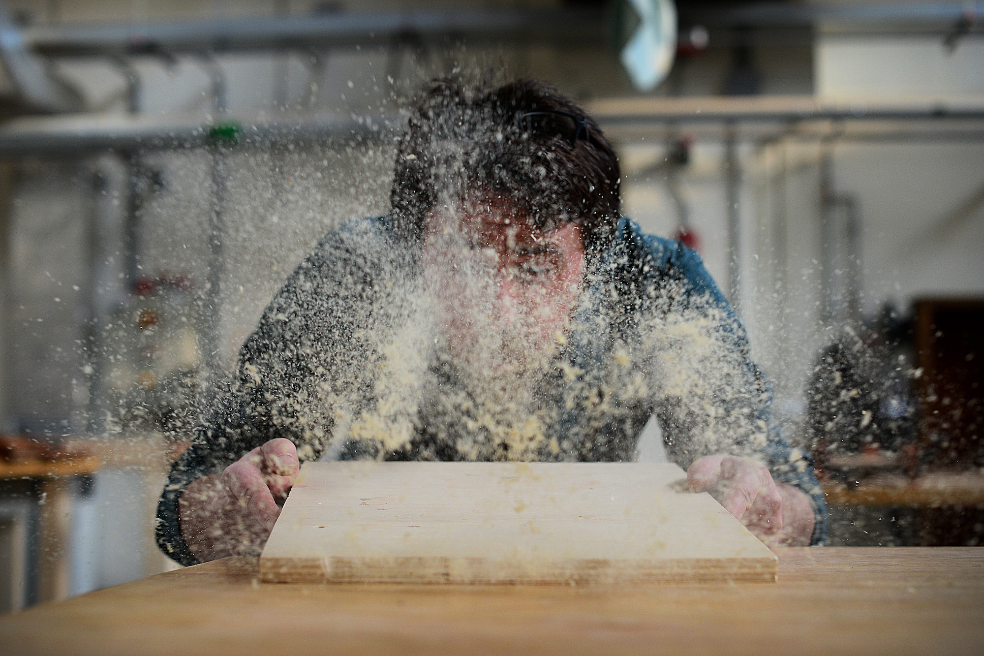 Stefano De Bortoli, 31st Force Support Squadron wood hobby shop manager, blows sawdust off a piece of wood, March 24, 2015, at Aviano Air Base, Italy. Bortoli provides wood working services and assists customers that use any self-help machinery and tools. (U.S. Air Force photo by Senior Airman Matthew Lotz/Released)