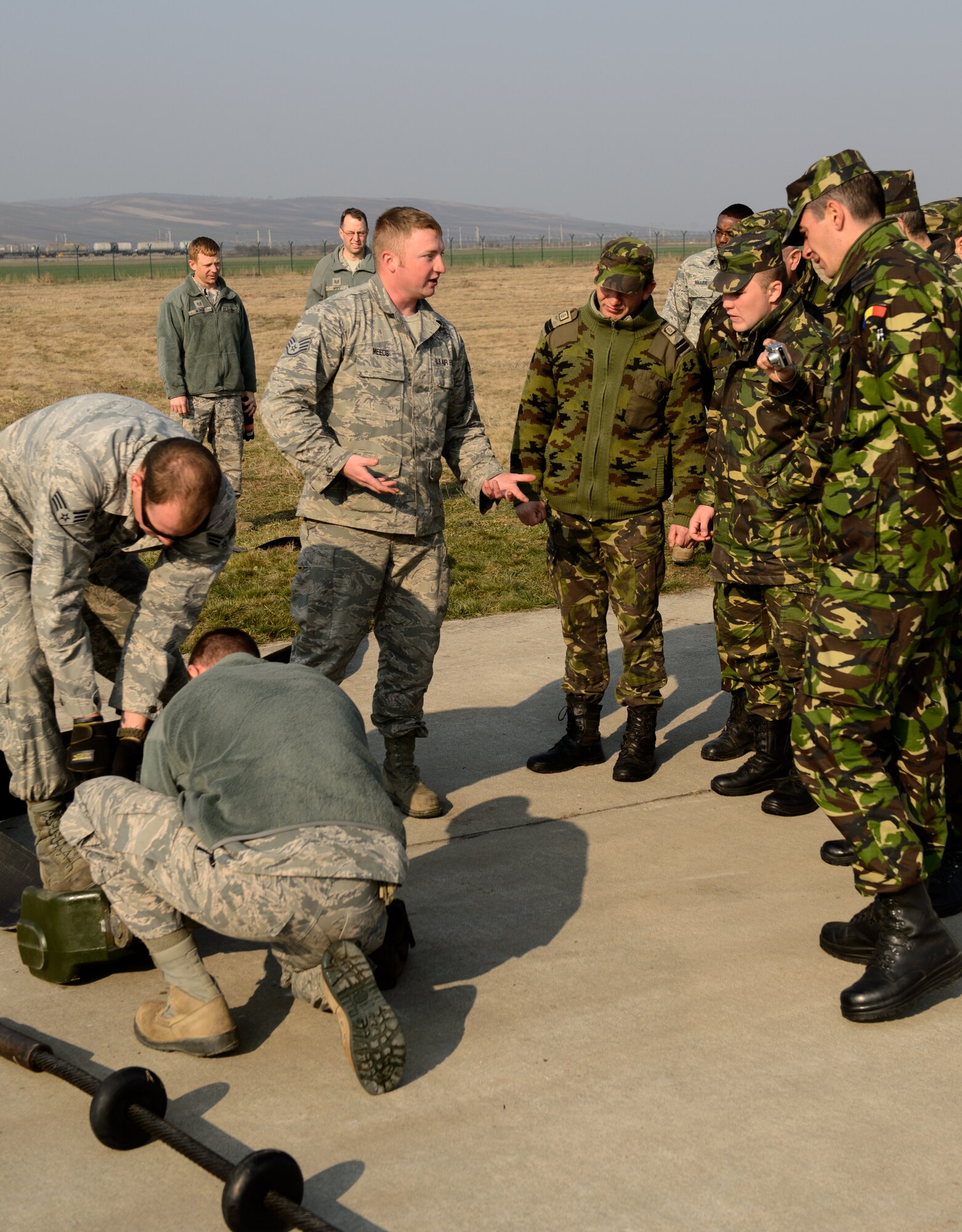 Staff Sgt. Aaryn Meeds, 435th Construction and Training Squadron power production technician, center, discusses the mobile aircraft arresting system during Dacian Warhawk, a two-week training mission designed to increase the interoperability between U.S. and Romanian air forces,  at Campia Turzii, Romania, March 24, 2015. Meeds and his team taught the Romanian airmen the basic functions of the MAAS in order to improve their knowledge and understanding of the system for future use in combined operations. (U.S. Air Force photo/Staff Sgt. Armando A. Schwier-Morales)