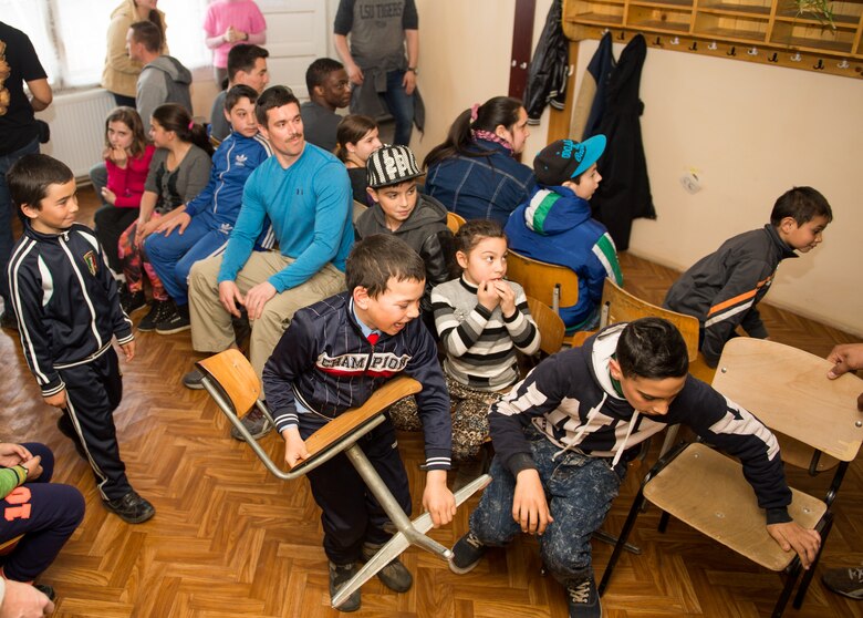 Airmen from the 52nd Fighter Wing and 435th Air Ground Operations Wing and children race to take a seat during musical chairs at a community center at Campia Turzii, Romania, March 20, 2015. The Airmen visited the center for less-than-fortunate children from the local area to bring gifts, teach English and play games with more than 50 children attending an after school education program. (U.S. Air Force photo/Staff Sgt. Armando A. Schwier-Morales)