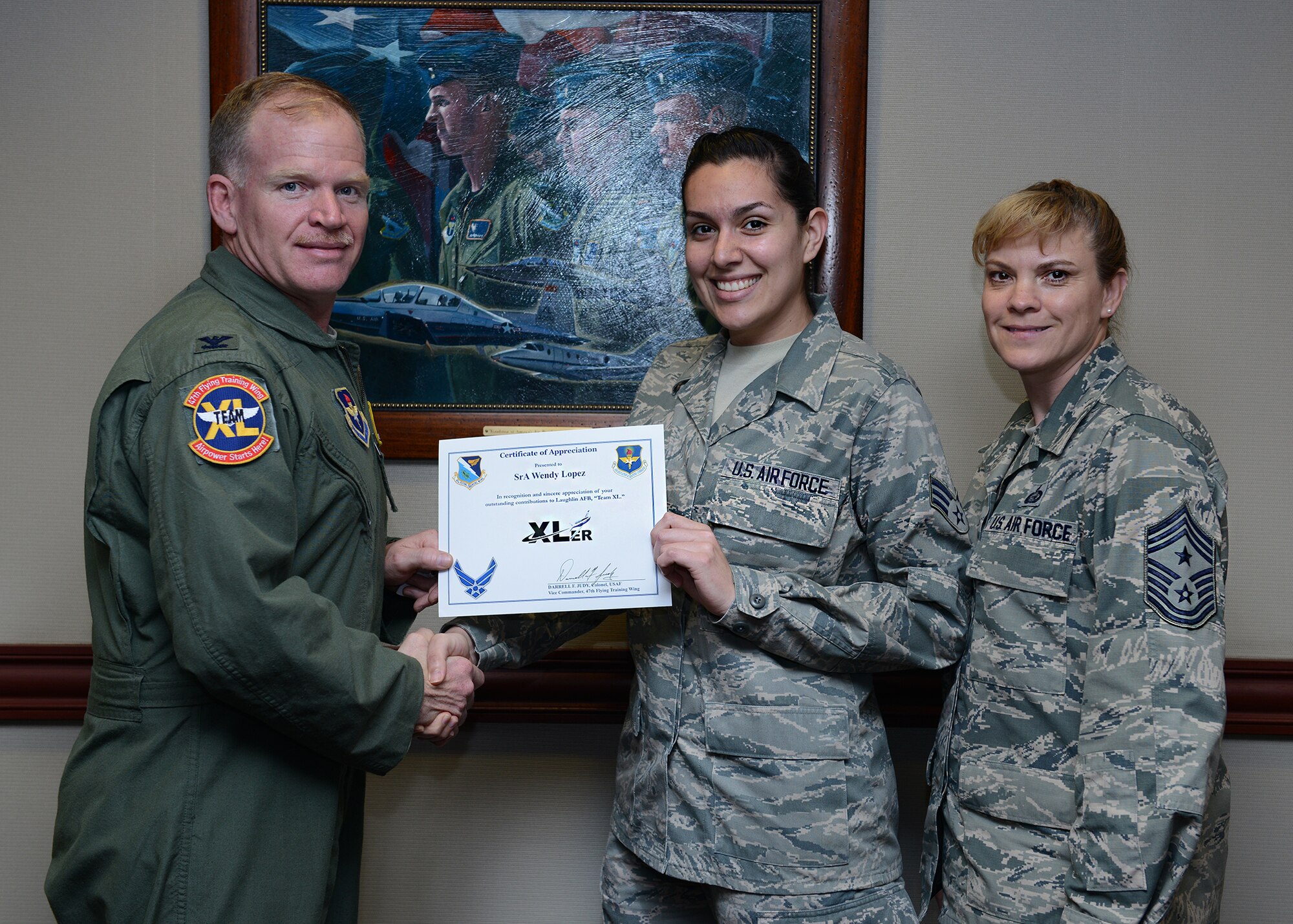 Senior Airman Wendy Lopez, center, 47th Flying Training Wing Command Post controller, poses with Col. Darrell Judy, 47th FTW vice commander and Chief Master Sgt. Teresa Clapper, 47th FTW command chief, after accepting the XLer of the week award here March 18, 2015. The XLer is a weekly award chosen by wing leadership and was presented to Lopez for her work in submitting a Commander Critical Information Requirement in a timely manner that allowed Air Education and Training Command to be notified in minimum time. (U.S. Air Force photo by Airman 1st Class Jimmie D. Pike)(Released)