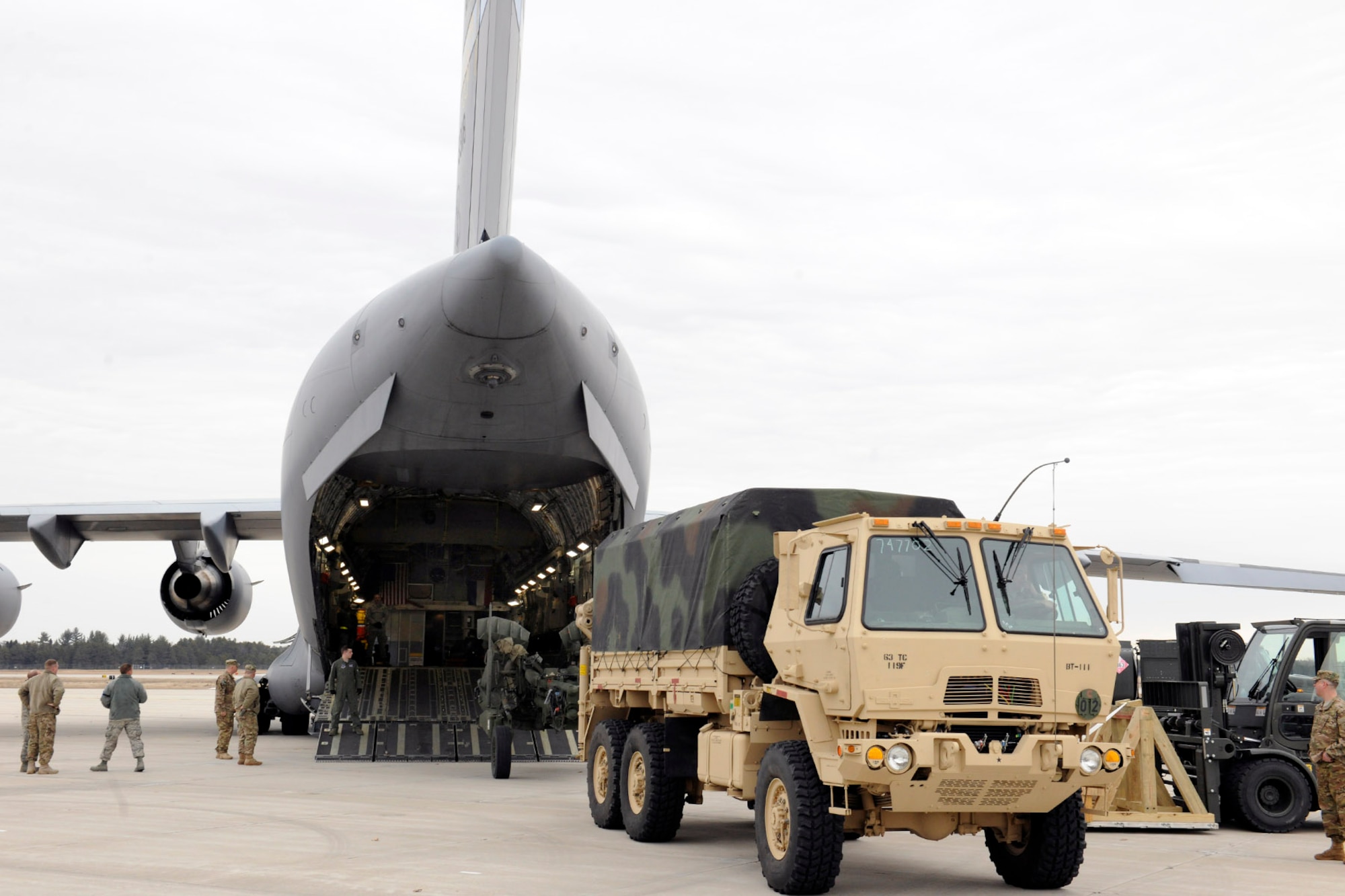 150319-Z-EZ686-314 – Soldiers, trucks, artillery pieces and other equipment from the 119th Field Artillery, Michigan Army National Guard, await loading into a C-17 Globemaster III operated by the Mississippi Air National Guard at the Alpena Combat Readiness Training Center, Mich., March 19, 2015. The equipment was loaded by Airmen from the 127th Logistics Readiness Squadron of the Michigan Air National Guard, which provides aerial port services to military units across the state of Michigan. (U.S. Air National Guard photo by Master Sgt. David Kujawa) 
