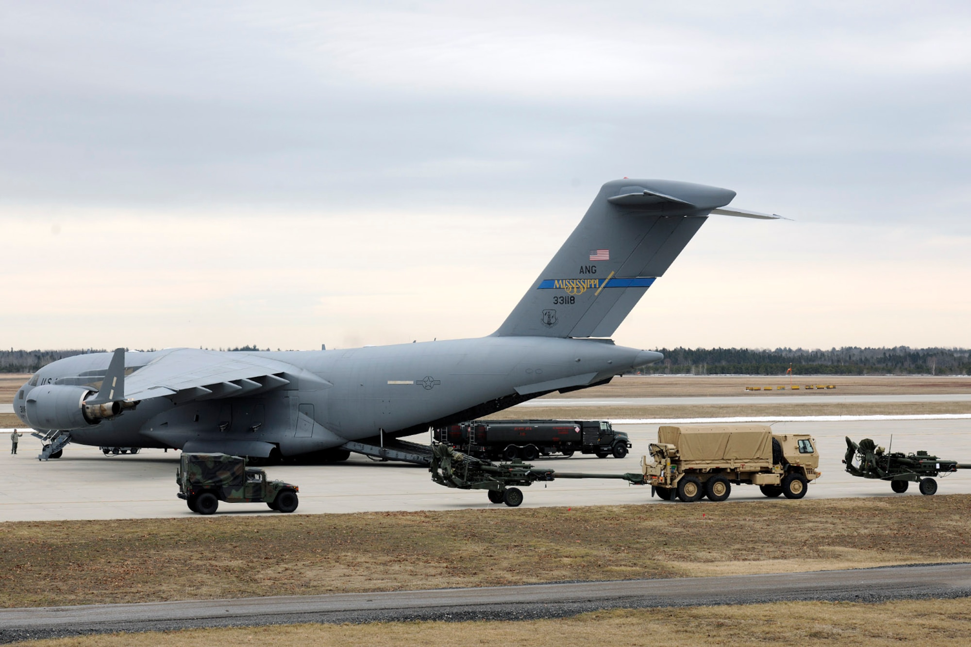 150319-Z-EZ686-244 – Soldiers, trucks, artillery pieces and other equipment from the 119th Field Artillery, Michigan Army National Guard, await loading into a C-17 Globemaster III operated by the Mississippi Air National Guard at the Alpena Combat Readiness Training Center, Mich., March 19, 2015. The equipment was loaded by Airmen from the 127th Logistics Readiness Squadron of the Michigan Air National Guard, which provides aerial port services to military units across the state of Michigan. (U.S. Air National Guard photo by Master Sgt. David Kujawa) 
