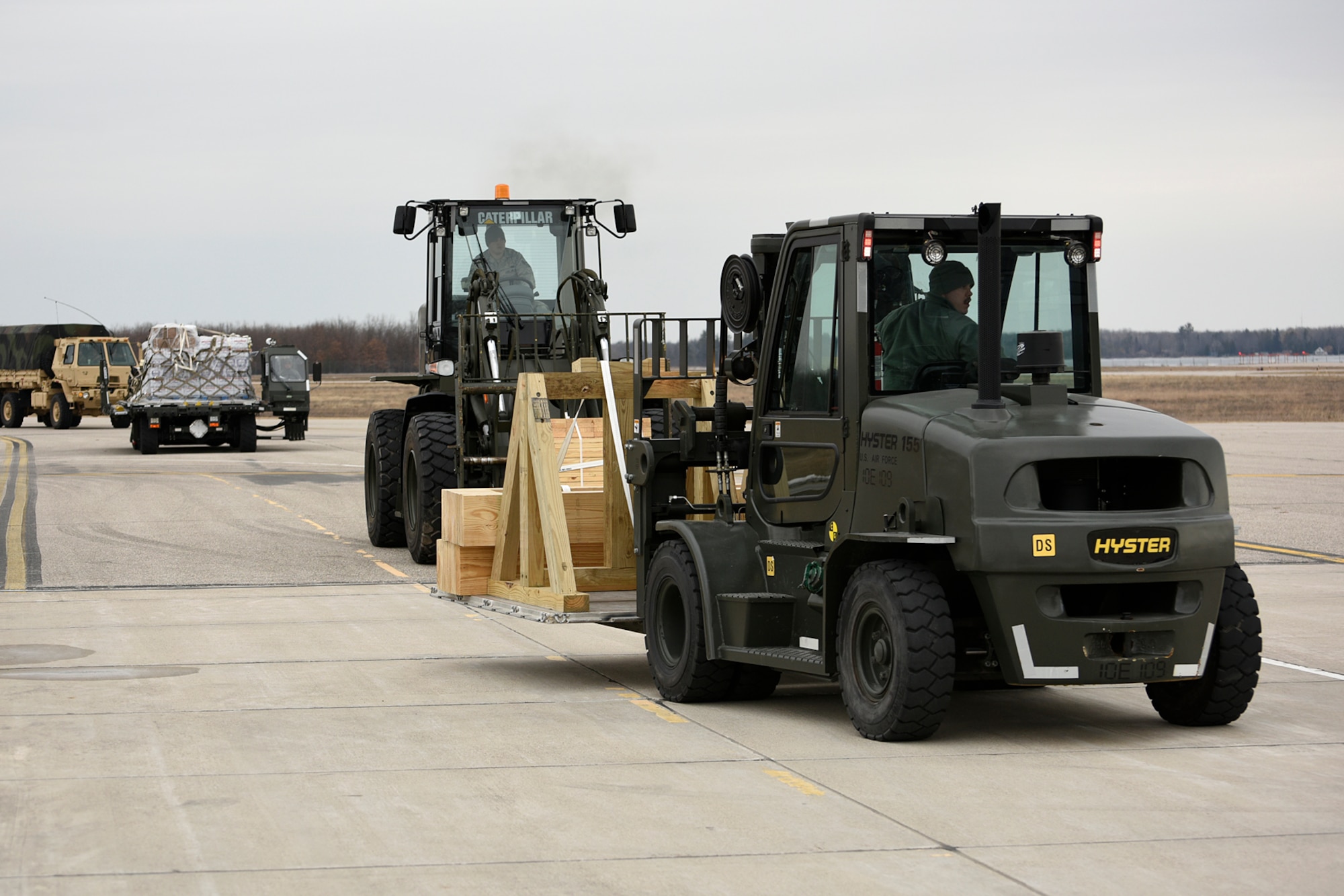 The 127th Logistics Readiness Squadron moves equipment and ammunition across the flight line at the Alpena Combat Readiness Training Center, Mich., March 20, 2015. They are loading the equipment onto three Air National Guard jets, in support of a mobilization exercise for the Michigan Army National Guard. 127th LRS provides transportation, aerial port, supply and readiness support to the 127th Wing. (U.S. Air National Guard photo by Senior Airman Ryan Zeski/Released)