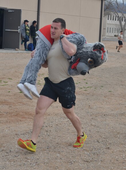 Airman 1st Class Steven Galvao, 342nd Training Squadron, carries Lucy Lobo, the University of New Mexico mascot during one of the fitness challenge at the Drug Enforcement Agency Maltz Challenge at Kirtland Air Force Base, New Mexico, March 20, 2015. The competition honored fallen pararescueman Master Sgt. Michael Maltz, as well as Albuquerque native Army Pfc. Zachary Lovejoy, an Army paratrooper killed in 2010 in Afghanistan. (U.S. Air Force photo by Todd Berenger)