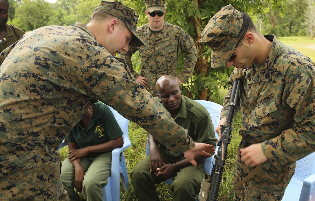 Lance Cpl. Jeremy Cuthrell, left, shows Tanzanian park rangers proper weapons safety procedures on an M4 assault rifle held by Lance Cpl. Julian Filgueiras, a rifleman with Special-Purpose Marine Air-Ground Task Force Crisis Response-Africa, training with the rangers at the Selous Game Reserve in Matambwe, Tanzania, March 2, 2015. The Marines and Sailors of Special-Purpose Marine Air-Ground Task Force Crisis Response-Africa will spend the next several weeks teaching the Tanzanian park rangers infantry skills such as patrolling, offensive tactics, land navigation and mounted operations to aid in countering illicit trafficking. (U.S. Marine Corps photo by Lance Cpl. Lucas J.Hopkins/Released)