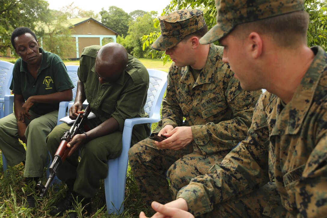 A Tanzanian park ranger shows Lance Cpls. Kyle McAuliffe, right, and Jeremy Cuthrell, far right, infantrymen with Special-Purpose Marine Air-Ground Task Force Crisis Response-Africa, how to disassemble an AKM assault rifle at the Selous Game Reserve in Matambwe, Tanzania, March 2, 2015.. Approximately 15 Marines and Sailors  with the unit taught weapons safety and marksmanship techniques to the park rangers as part of an ongoing effort to counter illicit-trafficking. (U.S. Marine Corps photo by Lance Cpl. Lucas J. Hopkins/Released)