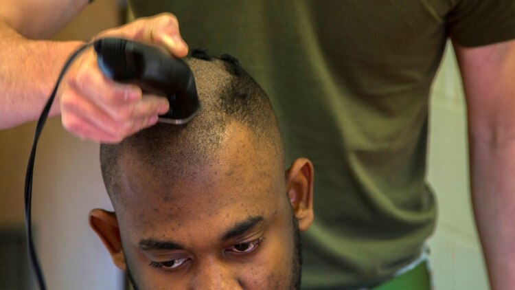 Lance Cpl. Stedji Legros, a rifleman with 1st Platoon, Kilo Company, 3rd Battalion, 8th Marine Regiment, receives a haircut in the barracks aboard Marine Corps Base Camp Lejeune, N.C., March 24, 2015. Marines with the platoon volunteered for their heads to be shaved in support of the platoon sergeant's daughter, Katie Whatley, who is fighting cancer.