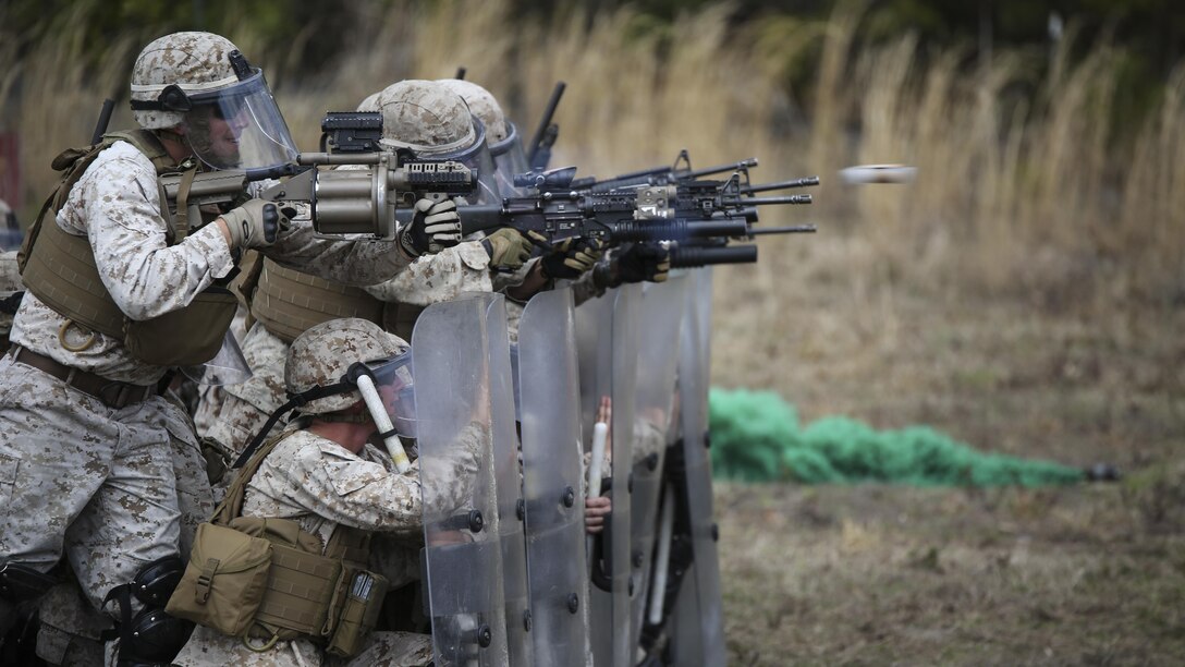 Marines with Battery and Golf Co., 2nd Battalion, 6th Marines, fire their M203 and M32 grenade launchers with non-lethal rounds down range during a riot control exercise aboard Camp Lejeune, N.C., March 24, 2015. The Marines marched in formation through multiple mock rioters, encountering flash bang grenades and smoke bombs while using their shields as a stable line of defense. 