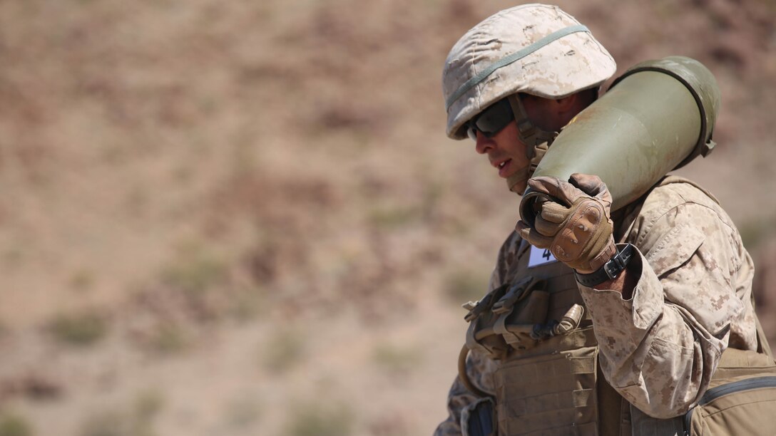 Cpl. Joshua J. Syverson, combat engineer, Engineer Platoon, Headquarters and Service Company, Ground Combat Element Integrated Task Force, carries a 155mm shell during cache reduction as part of a Marine Corps Operational Test and Evaluation Activity assessment at Range 114, Marine Corps Air Ground Combat Center Twentynine Palms, California, March 23, 2015.  From October 2014 to July 2015, the GCEITF will conduct individual and collective level skills training in designated ground combat arms occupational specialties in order to facilitate the standards-based assessment of the physical performance of Marines in a simulated operating environment performing specific ground combat arms tasks. 