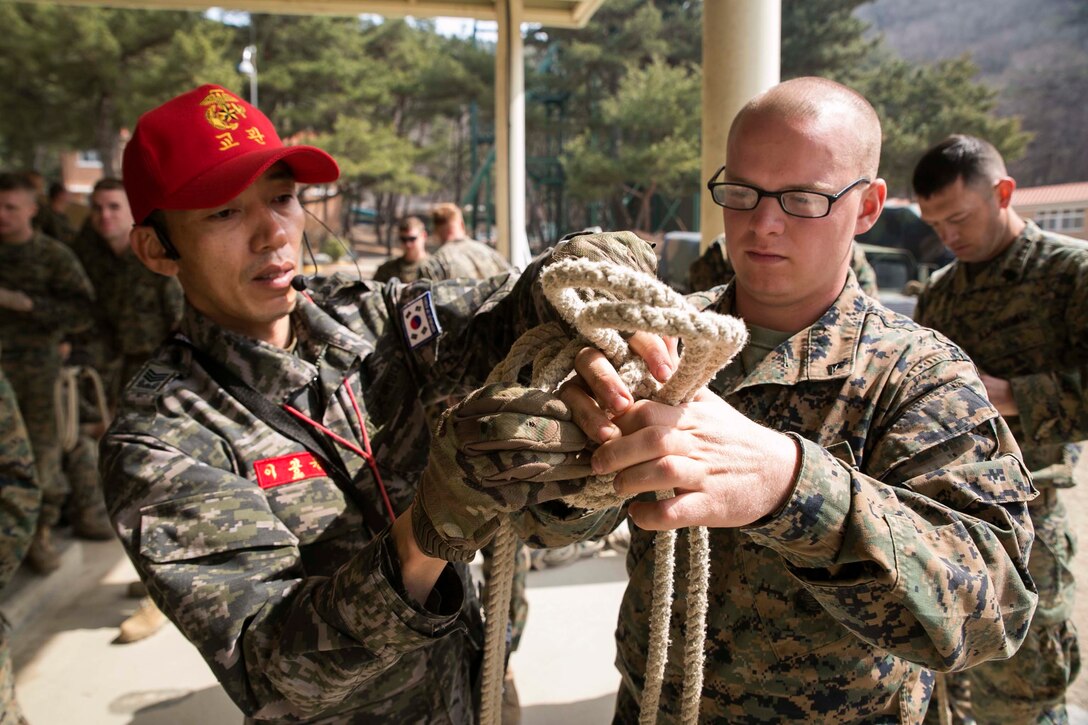 Republic of Korea Marine Master Sgt. Gwang Yoon Lee, left, shows U.S. Marine Lance Cpl. Tyler C. Voge a type of knot used when rappelling March 16 at the 1st Republic of Korea Marine Division Mountain Warfare Training Center in Pohang, South Korea. The Marines completed a five day mountain warfare training course led by ROK Marines with Mountain Warfare Training Unit, 1st ROK Marine Division as part of Korean Marine Exchange Program 15-14.2, a small-unit training exercise, which enhances the combat readiness and interoperability of the two forces. Voge, from Kewaskum, Wisconsin, is a mortarman with Weapons Company, 3rd Battalion, 2nd Marine Regiment, currently assigned to 4th Marine Regiment under the unit deployment program.