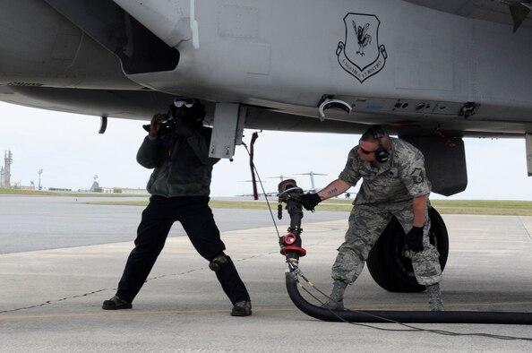 U.S. Air Force Master Sgt. Christian Schweitzer, 18th Logistics Readiness Squadron fuels operator, hands a fuel hose to Senior Airman Johnny Brown, 67th Aircraft Maintenance Unit crew chief, to refuel an F-15C Eagle during a sortie surge on Kadena Air Base, Japan, March 25, 2015. The surge allows the unit to get ahead of the flying-hour program and gives them the ability to test their maximum production capacity. (U.S. Air Force photo by Staff Sgt. Marcus Morris)