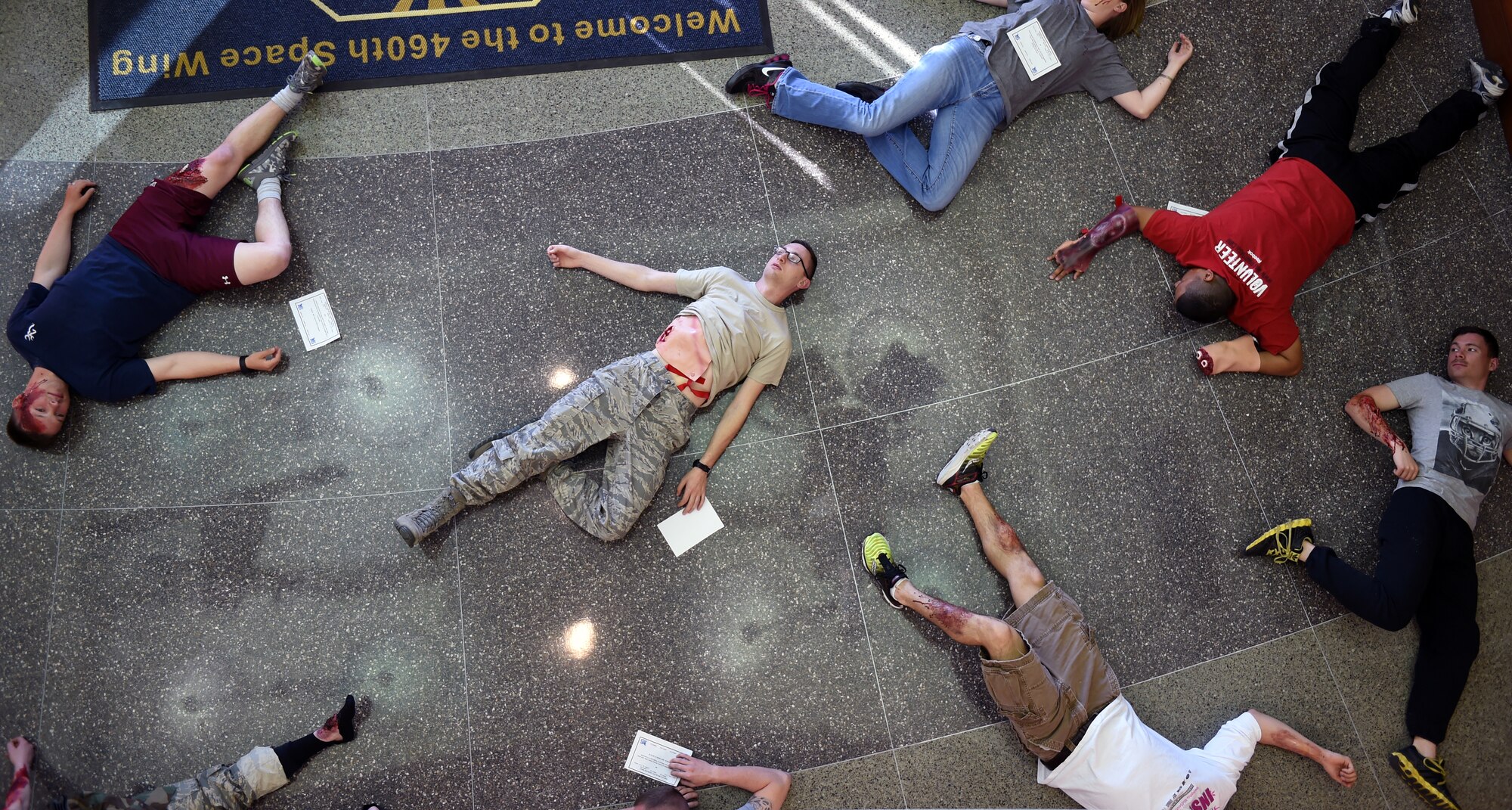 Team Buckley members lay in the lobby of the 460th Space Wing Headquarters building with simulated injuries during the Panther Lighting exercise March 25, 2015, on Buckley Air Force Base, Colo. Panther Lightning is Buckley AFB’s version of the Strategic Command exercise, Global Lightning, which is an Air Force-wide exercise that focuses on all combatant commands and their missions. (U.S. Air Force photo by Airman 1st Class Emily E. Amyotte/Released)