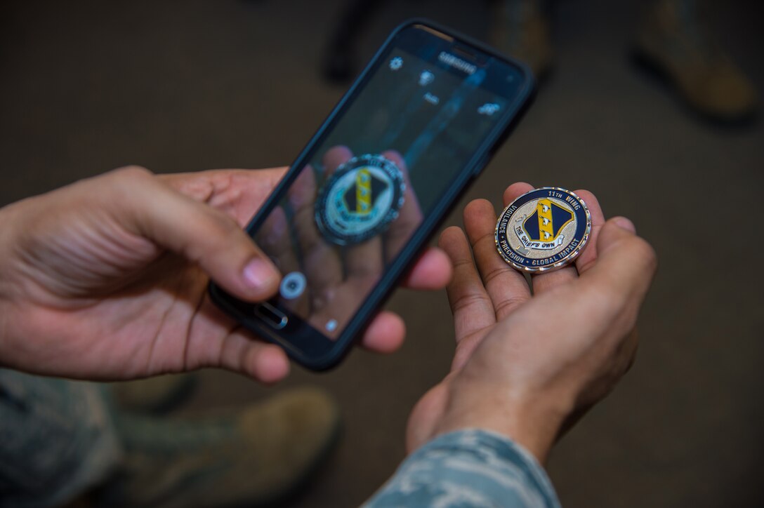 Tech. Sgt. Alfred Brooks, 89th Operational Support Squadron/Operational Weather Squadron airfield services NCO In-Charge, takes a photo of his new coin at the weather flight office on Joint Base Andrews, Md., March 13th, 2015. He took the photo with his phone with plans to share the news with friends and family. The 89 OSS/OSW was recognized by Col. Brad Hoagland, JBA/11th Wing commander, for correctly forecasted eight out of eight winter weather system. (U.S. Air Force photo/Airman 1st Class Philip Bryant)