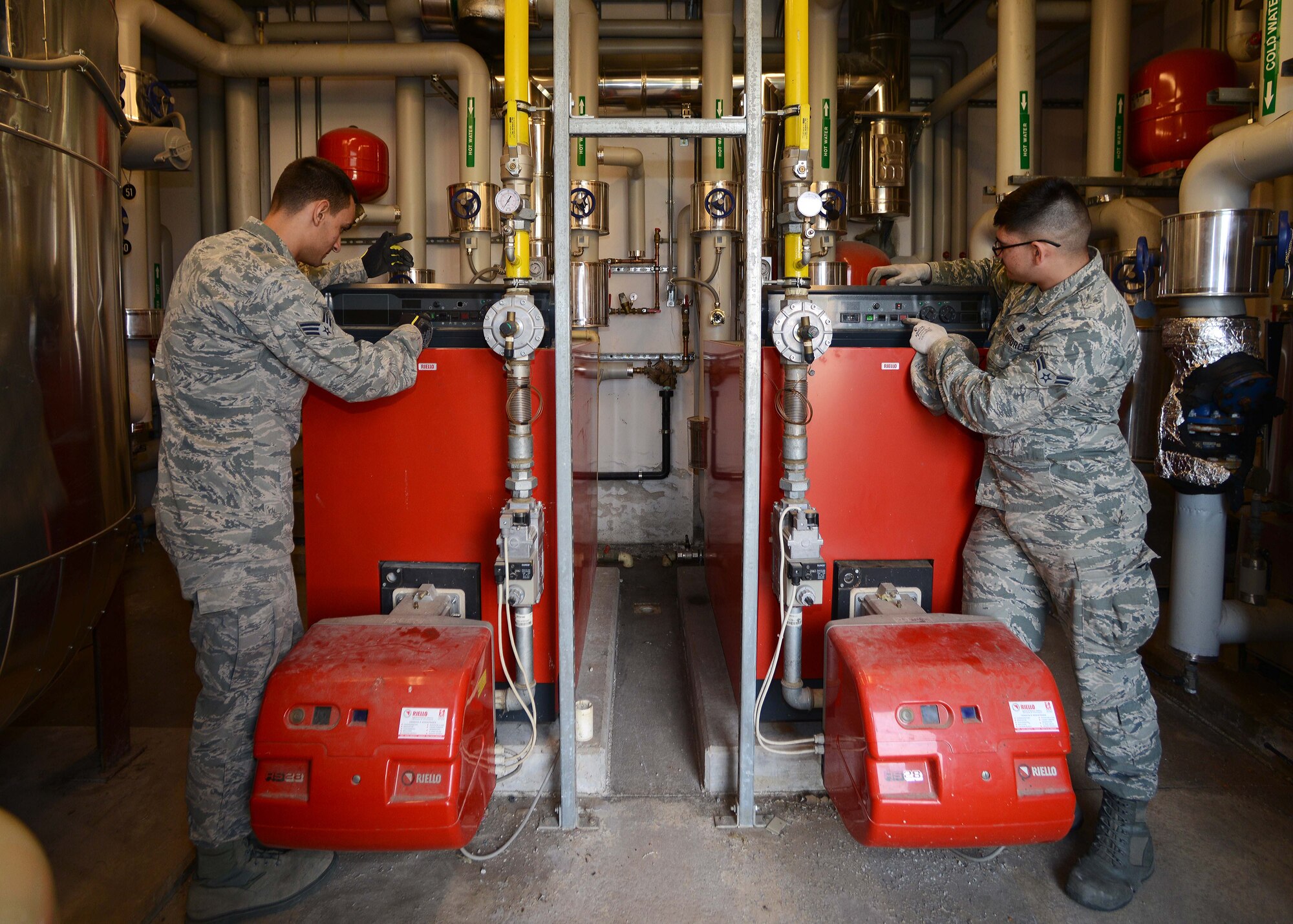(From left) U.S. Air Force Senior Airman Colin Josephson and Airman 1st Class Jedadiah Floyd, 31st Civil Engineer Squadron heating, ventilation, air conditioning and refrigeration technicians, inspect water and air boilers in the dormitories, March 24, 2015, at Aviano Air Base, Italy. During “no heat, no cool” season, all heating systems are shut off to prepare for the air conditioning systems. (U.S. Air Force photo by Airman 1st Class Deana Heitzman/Released)