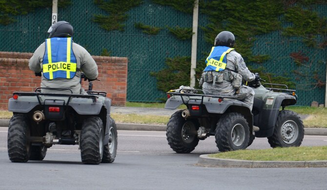 U.S. Air Force Chief Master Sgt. Tracy Jones, left, 100th Air Refueling Wing command chief, and U.S. Air Force Chief Master Sgt. Chad W. Bickley, right, 100th Security Forces Squadron security forces manager from Castlewood, Va., join the road heading for the main gate March 19, 2015, on RAF Mildenhall, England. Following a meet and greet, Jones and Bickley rode all-terrain vehicles to the main gate to meet fellow military members, their families and civilians as they arrived on base. (U.S. Air Force photo by Gina Randall/Released)