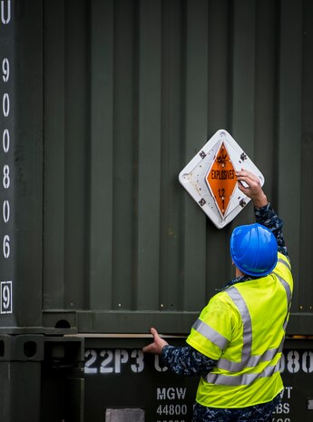 A Sailor with the Navy Munitions Command Unit Charleston adjusts an explosives warning sign March, 25, 2015, near the USNS Lewis and Clark (T-AKE-1) at Naval Weapons Station Wharf Alpha in Charleston, S.C. The Lewis and Clark is a replenishment naval vessel. In 2012, USNS Lewis and Clark became one of 14 ships that comprise the United States Marine Corps Maritime Prepositioning Program. Prepositioning ships provide quick and efficient movement of military equipment/supplies between operating areas without reliance on other nations' transportation networks. These ships give U.S. regional combatant commanders the assurance that they will have what they need to quickly respond in a crisis - anywhere, anytime. (U.S. Air Force photo/Airman 1st Class Clayton Cupit)
