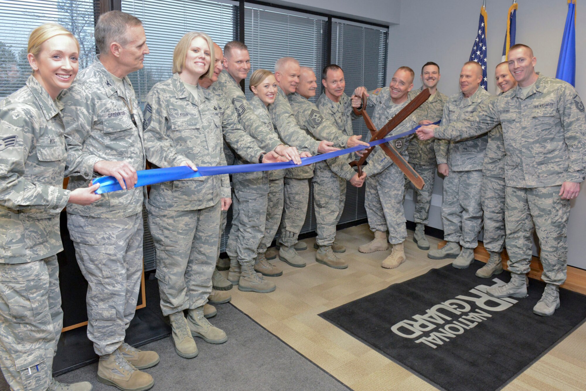 The Adjutant General of the Iowa National Guard, Maj. Gen. Timothy Orr (scissors, right), and 132d Wing (132WG) Commander, Col. Kevin Heer (scissors, left), cut the ribbon as members of the Iowa Air and Army National Guard celebrate the opening of the 132WG, Des Moines, Iowa off-site Recruiting Operation Center during a ribbon cutting ceremony held at the new Recruiting Operation Center in West Des Moines, Iowa on Tuesday, March 24, 2015.  Leaders of the Iowa National Guard, leaders of the 132WG and members of the 132WG Force Support Squadron hold the ribbon as it is being cut.  (U.S. Air National Guard photo by Staff Sgt. Linda K. Burger/Released)