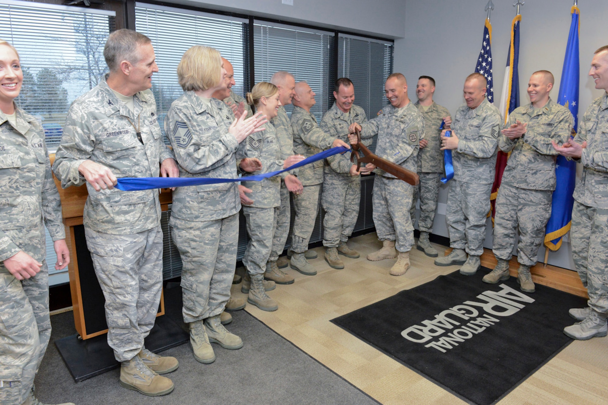 The Adjutant General of the Iowa National Guard, Maj. Gen. Timothy Orr (scissors, right), and 132d Wing (132WG) Commander, Col. Kevin Heer (scissors, left), cut the ribbon as members of the Iowa Air and Army National Guard celebrate the opening of the 132WG, Des Moines, Iowa off-site Recruiting Operation Center during a ribbon cutting ceremony held at the new Recruiting Operation Center in West Des Moines, Iowa on Tuesday, March 24, 2015.  Leaders of the Iowa National Guard, leaders of the 132WG and members of the 132WG Force Support Squadron hold the ribbon as it is being cut.  (U.S. Air National Guard photo by Staff Sgt. Linda K. Burger/Released)