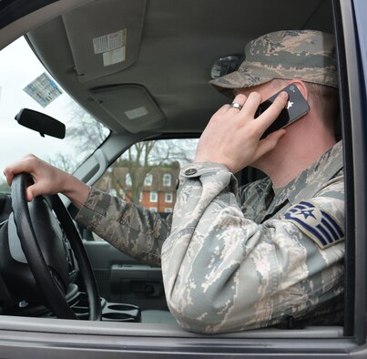U.S. Air Force Staff Sgt. Jason Prentice, 100th Logistics Readiness Squadron NCO in charge of operators, records and licensing from Portland, Ore., demonstrates how talking on a cell phone while driving renders the driver unable to keep both hands on the streering wheel March 19, 2015, on RAF Mildenhall, England. The 100th Air Refueling Wing Safety Office runs a program where people can get involved and report unsafe driving. (U.S. Air Force photo by Gina Randall/Released) 