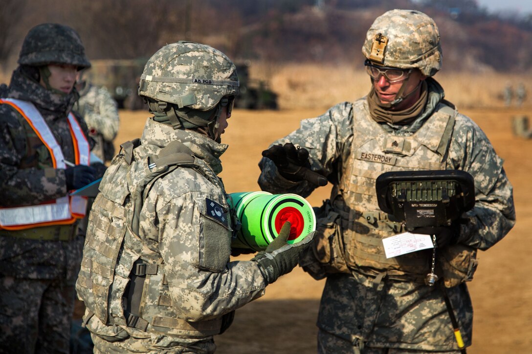 U.S. Army Sgt. Easterday, right, provides instructions to a soldier carrying a 155 mm charge to