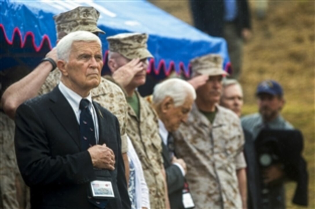 U.S. Marines and veterans render honor to the American flag during the playing of the national anthem during the commemoration of the 70th anniversary of the Battle of Iwo Jima at the Reunion of Honor memorial in Iwo To, Japan, March 21, 2015. 