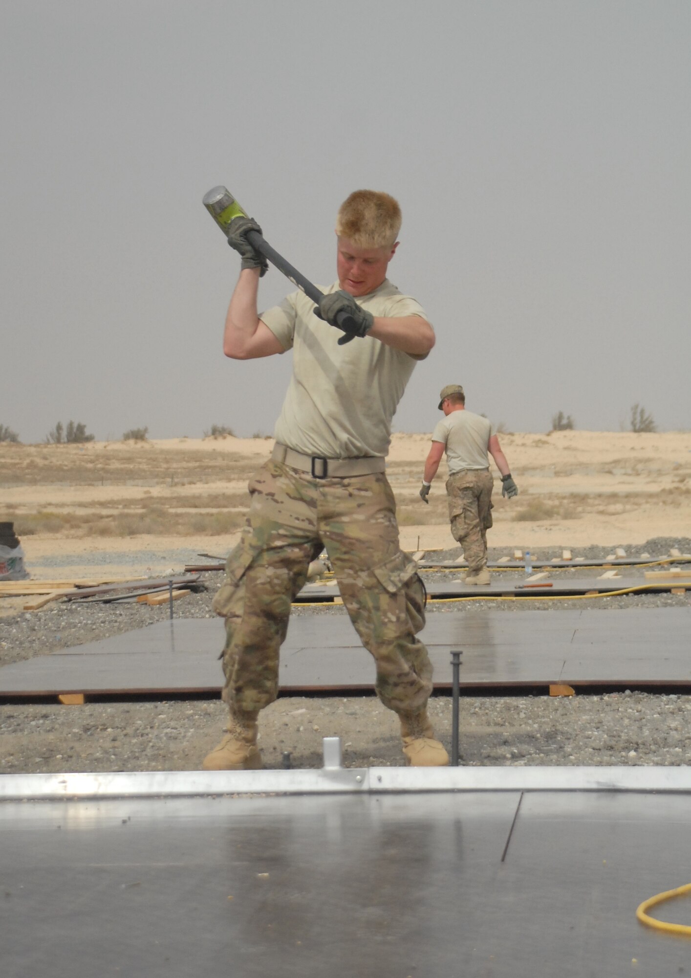 Spc. Kaleb Hazlett, 1313th Engineer Company heavy equipment operator, swings a sledge hammer while building a tent at the 332nd Air Expeditionary Group March 19, 2015.  Members of the Indiana National Guard came together to build 60 tents for personnel deployed in support of Operation Inherent Resolve. (U.S. Air Force photo by 1st Lt. Sarah Ruckriegle)