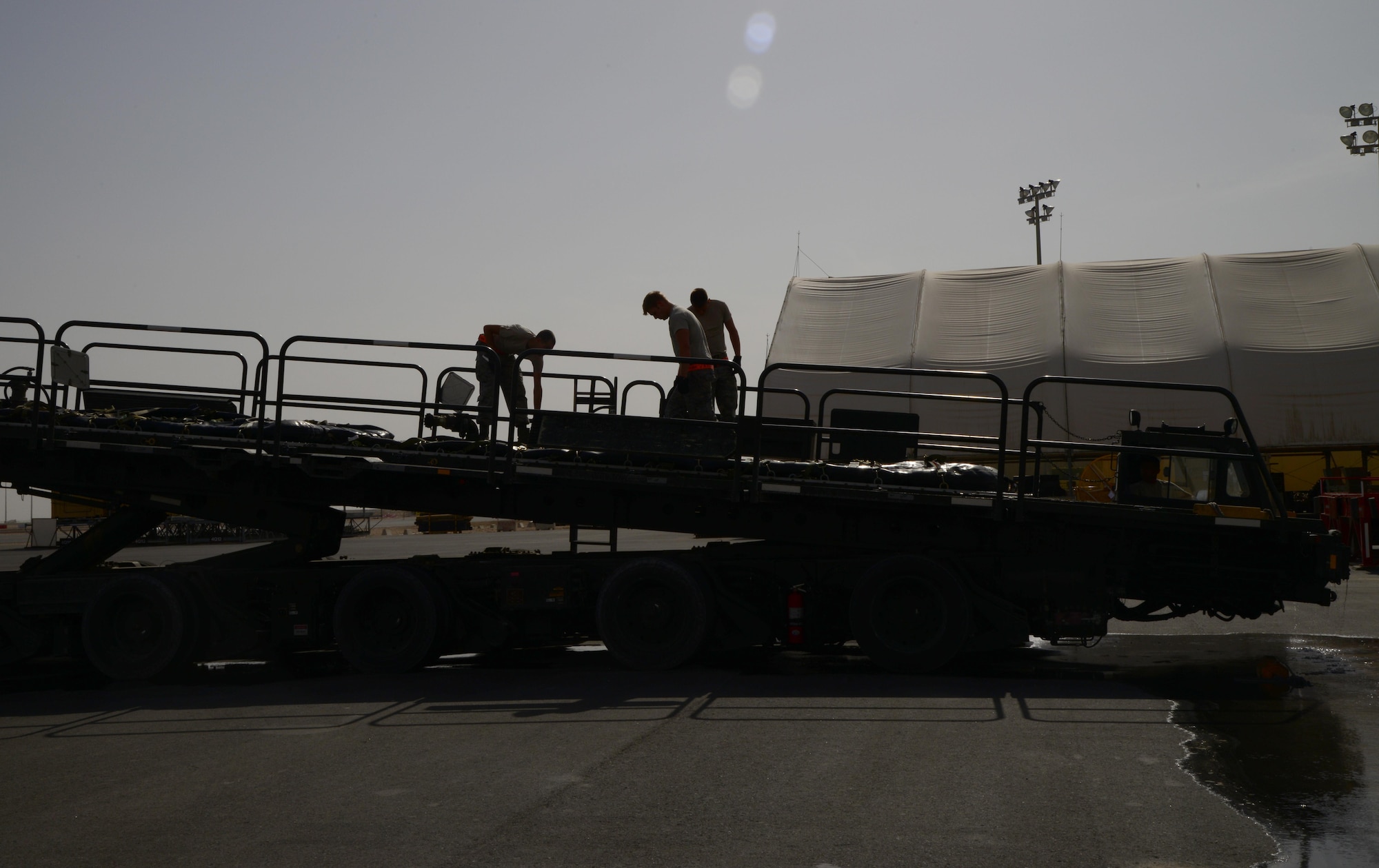 Airmen from the 8th Expeditionary Air Mobility Squadron air freight ramp services section drain water off of fuel bladders, March 23, 2015, at Al Udeid Air Base, Qatar. The ramp services section handles the loading and unloading of cargo and equipment pallets from different aircraft. Weekly, they support more than 75 missions where they load and unload more than 650 tons of cargo. (U.S. Air Force photo by Senior Airman Kia Atkins)