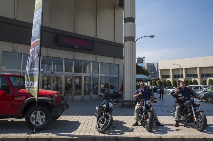 Jeffrey Mowatt, left, and Michael Livingston, right, independent sales representatives at Exchange New Car Sales aboard Marine Corps Air Station Iwakuni, Japan, pose for a picture, March 27, 2015. Exchange New Car Sales provides service members the opportunity to have a brand new car waiting for them when they go home.