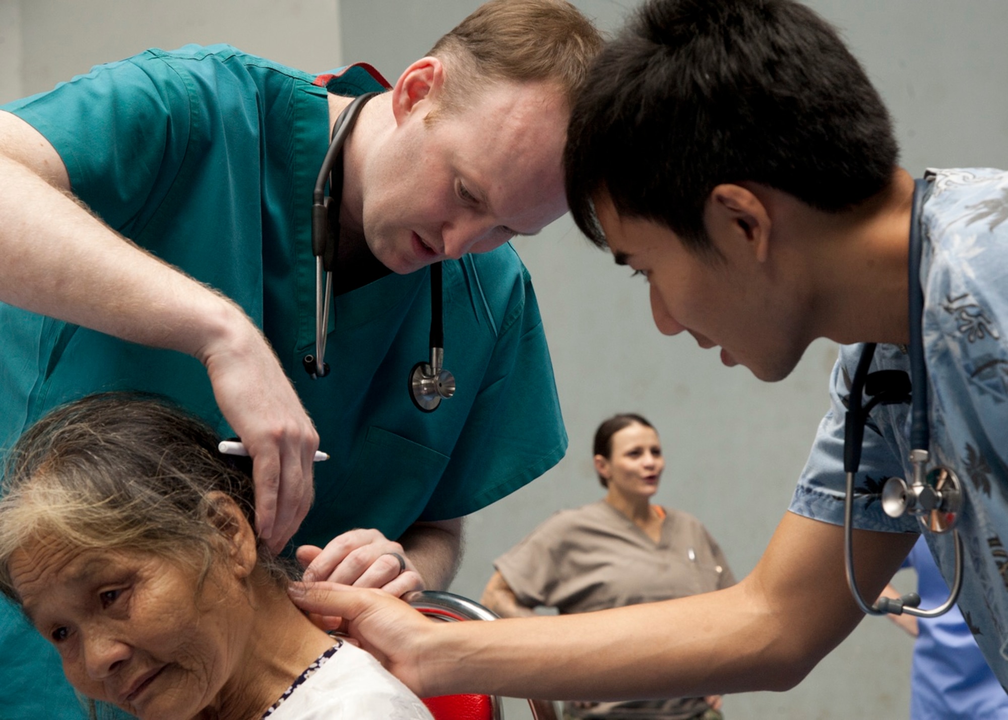 Capt. Aaron Goodrich and Republic of Singapore air force Lt. Jason Pek examine a patient during a Pacific Angel 15-3 human service outreach event March 24, 2015, at Dung Quat Culture-Sports Center, Quang Ngai Province, Vietnam. Pacific Angel is a multilateral humanitarian assistance civil military operation, which improves military-to-military partnerships in the Pacific while also providing medical health outreach, civic engineering projects, and subject matter exchanges among partner forces. Goodrich is assigned to the 35th Medical Group at Misawa Air Base, Japan. (U.S. Air Force photo/Staff Sgt. Tong Duong)