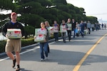 In this photo, Father Edward Ramatowski (left), 8th Fighter Wing chaplain, leads 35 volunteers from Kunsan Air Base to the Moses Infant Home carrying 32 boxes of donated diapers and wet wipes in Gunsan City, Republic of Korea, March 21, 2015. Thirty-five members from the 8th Fighter Wing and the deployed 120th Expeditionary Aircraft Maintenance Unit visited the children’s home to spend time with the 30 children living there. 