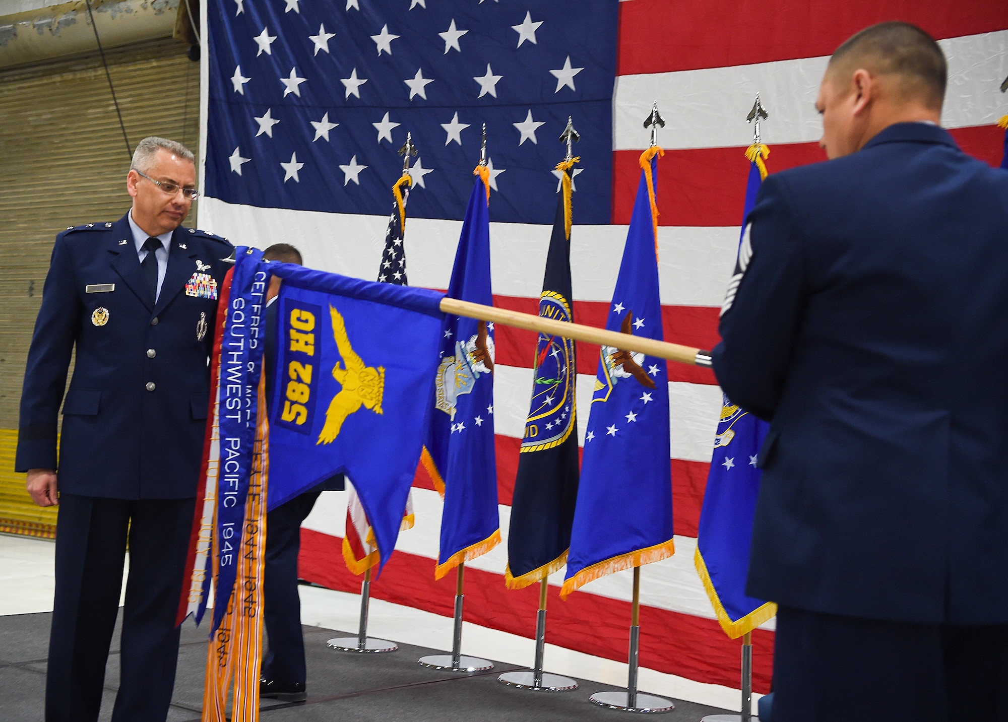 Maj. Gen. Jack Weinstein, Task Force 214 and 20th Air Force commander, unfurls the guidon of the 582nd Helicopter Group during an activation and assumption of command ceremony March 27, 2015, on F.E. Warren Air Force Base, Wyo. The new group, comprised of the three helicopter squadrons under 20th AF and the newly established 582nd Operations Support Squadron, was formed to improve mission effectiveness and standardize helicopter operations throughout the 20th AF. (U.S. Air Force photo by R.J. Oriez/Released)