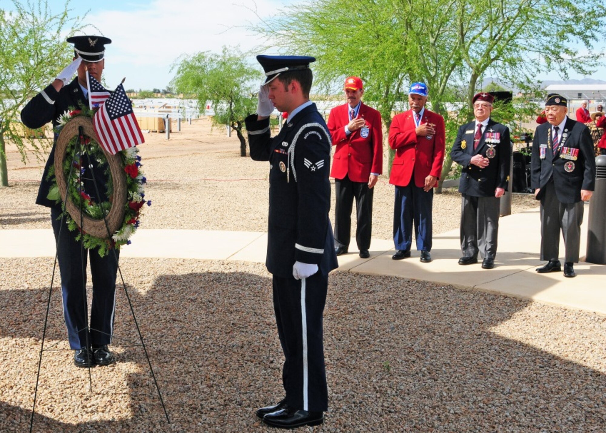 The Luke Air Force Base Honor Guard render military honors while (from left to right) Master Sgt. (Ret.) Rudolf Silas, Lt. Col. (Ret.) Robert Ashby, Tuskegee Airmen, Richard Blackfoot, Canadian WWII veteran, George Chow, Chinese Canadian WWII veteran, observe with hand on heart during the Tuskegee Airmen Commemoration Day ceremony March 26 at Luke Air Force Base, Ariz. (U.S. Air Force photo taken by Tech. Sgt. Louis Vega Jr.)