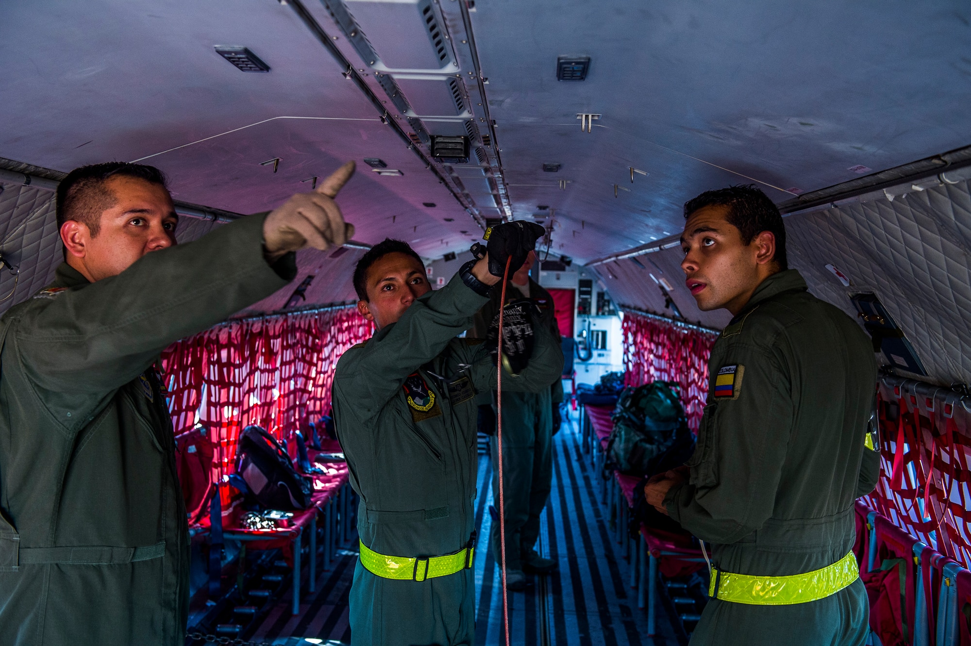 Tech. Sgt. Javier Borgesmartin, a loadmaster instructor for the 571st Mobility Support Advisory Squadron, shows Colombian Air Force loadmasters Tecnico Cuatro Javier Castillo and Sergio Leonardo Molina correct procedures for rigging a winch retriever cable on a Colombian Air Force Casa 295 aircraft in preparation for the first air drop with United States Air Force personnel aboard on March 3, 2015 at Marandua Air Force Base in Colombia, South America. (Photo by U.S. Air Force Tech. Sgt. Matthew Hannen)