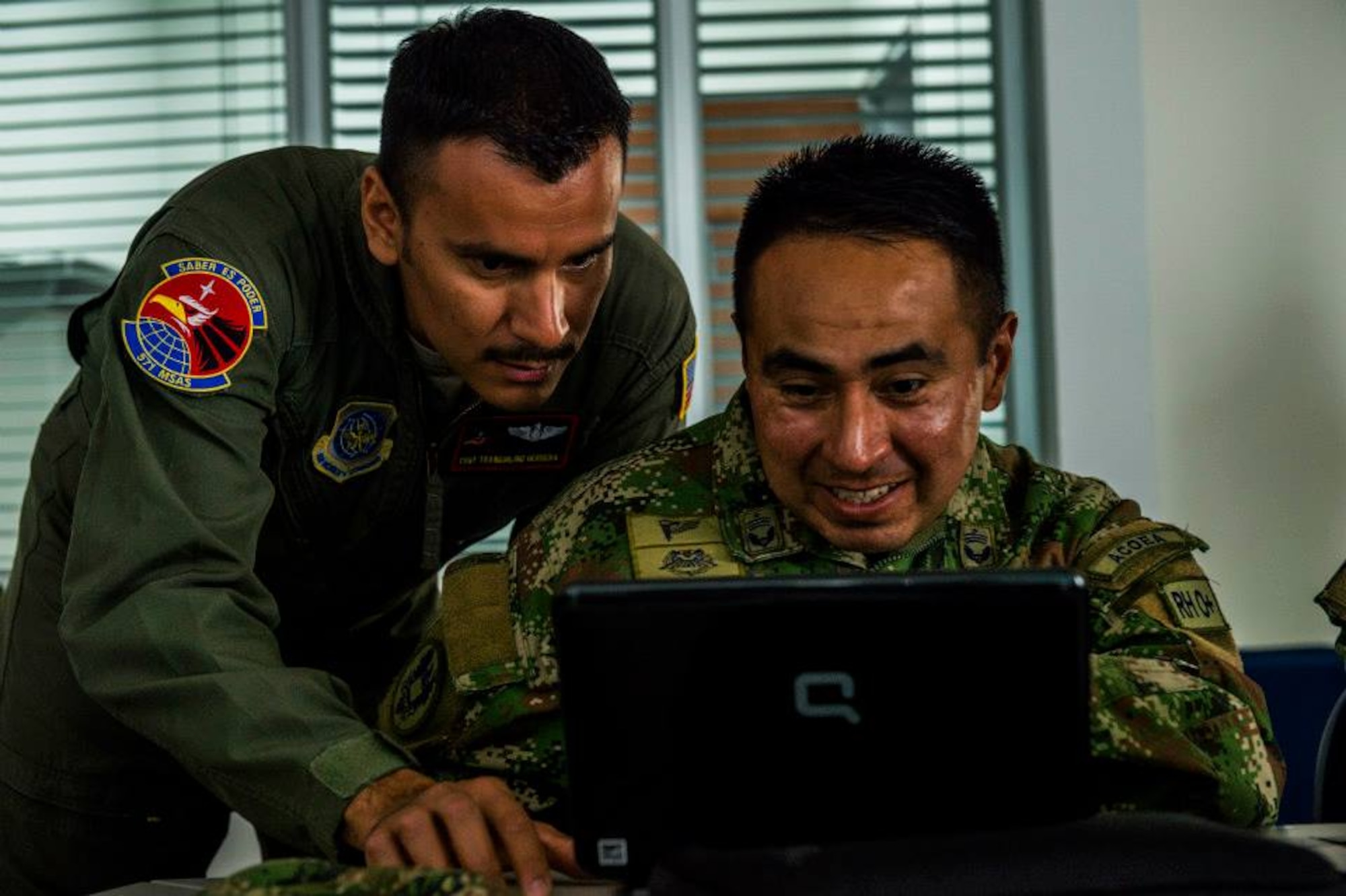 Tech. Sgt. Tranquilino Herrera, a loadmaster Air Advisor for the 571st Mobility Support Advisory Squadron, assist Colombian Air Force airmen Tecnico Primero Camilo Andres Rey with preparing a rigging checklist for the first air drop with United States Air Force personnel aboard on March 2, 2015 at CATAM Air Force Base, Colombia in South America. (Photo by U.S. Air Force Tech. Sgt. Matthew Hannen)